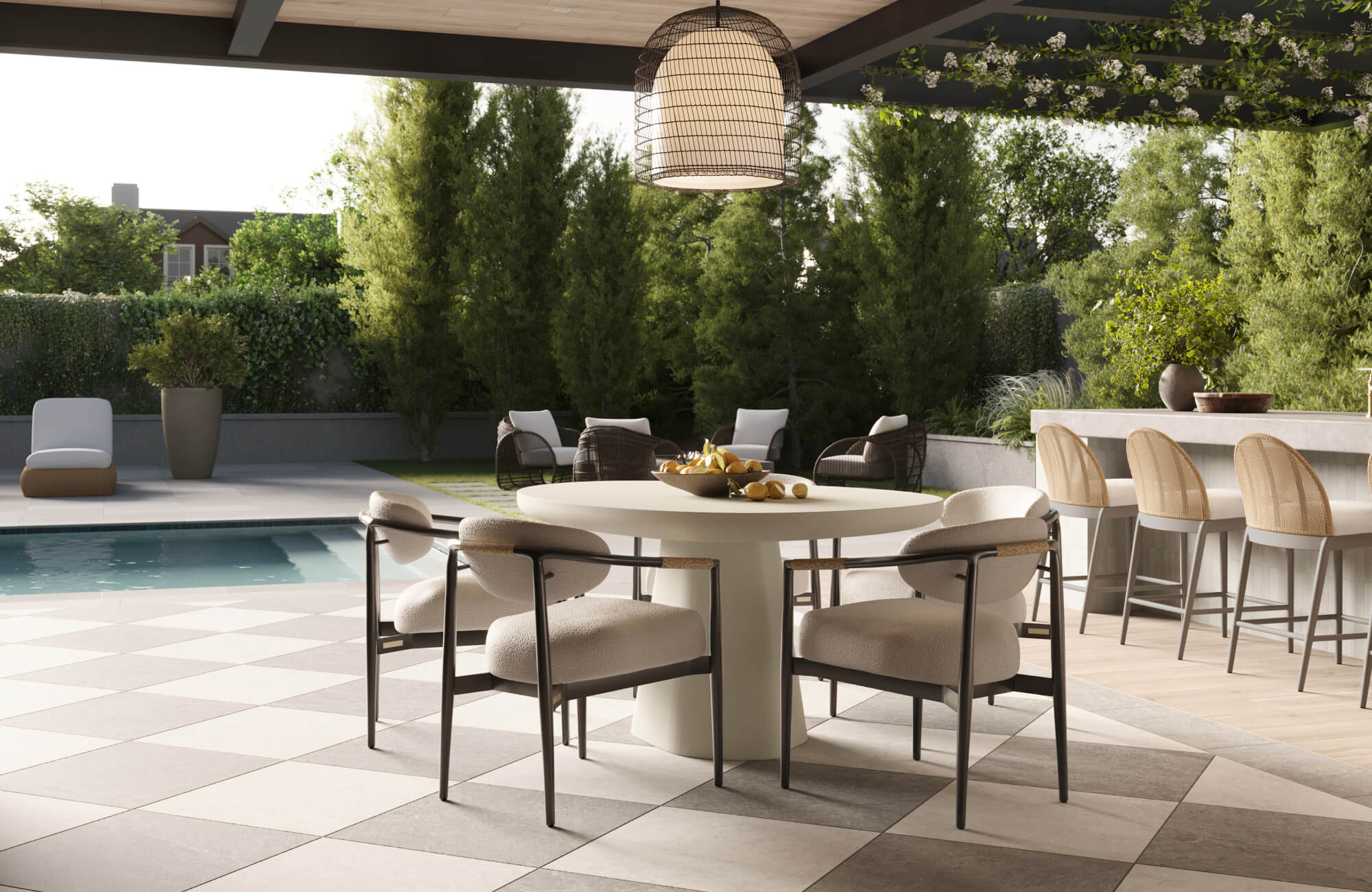 null A covered patio dining area overlooking a pool features a round pedestal table surrounded by upholstered chairs beneath a large woven pendant light.