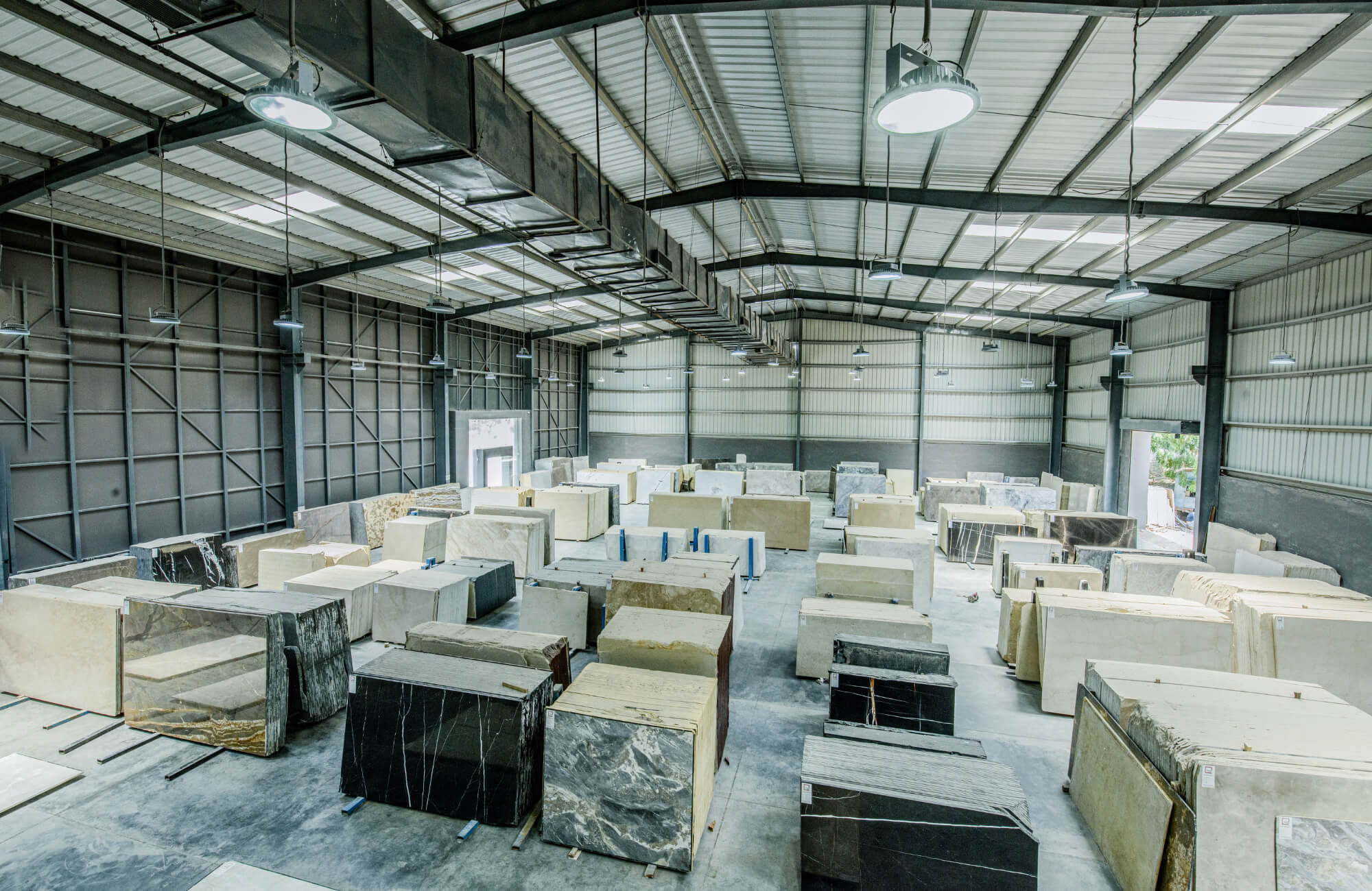 null Indoor warehouse filled with large marble and stone slabs of various colors and patterns, neatly arranged for selection and distribution.