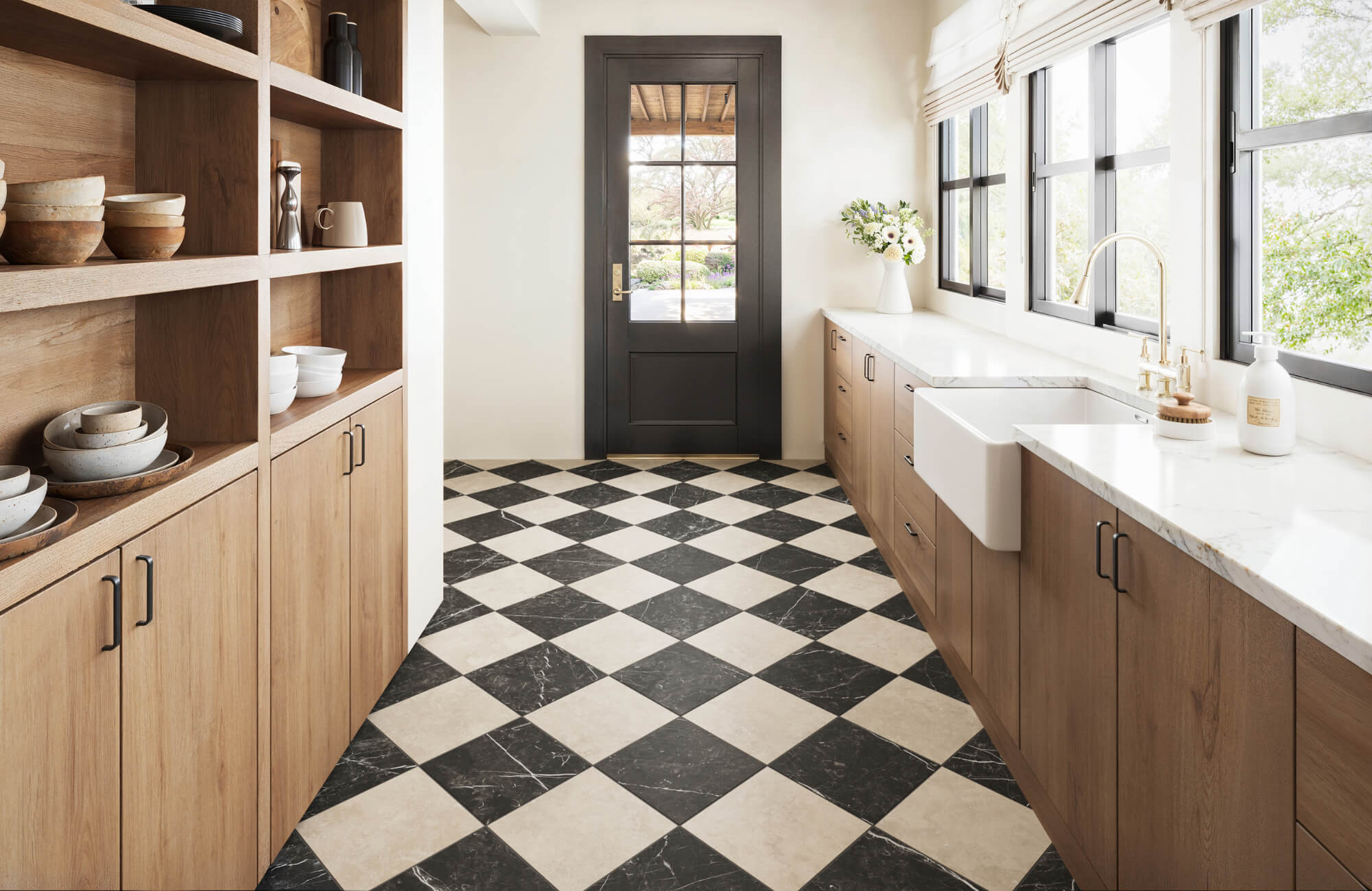 null Bright kitchen with wood cabinetry, farmhouse sink, and a striking black and white marble-look checkered tile floor in a diamond pattern.