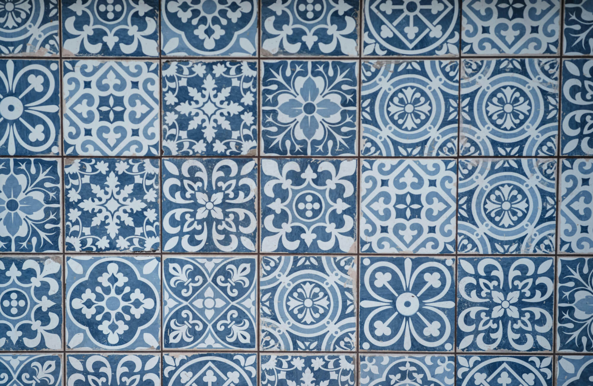 Vibrant blue and white patterned tiles arranged in a checkerboard layout, showcasing intricate floral and geometric motifs in boho style.