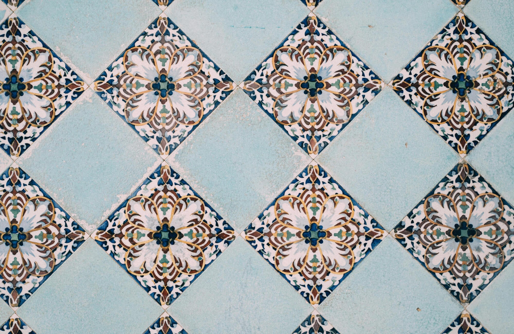 Intricate patterned tiles with a floral motif and pastel blue tiles in a checkered pattern, creating a visually stunning and decorative surface