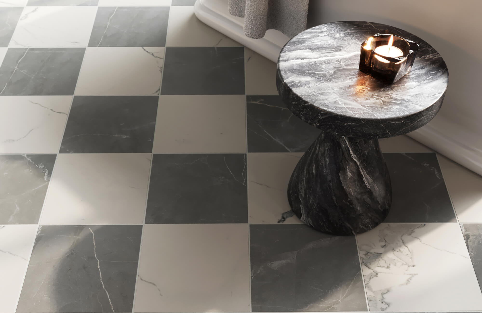 Close-up of a polished gray and white checkerboard tile floor paired with a sculpted black marble side table and candle.