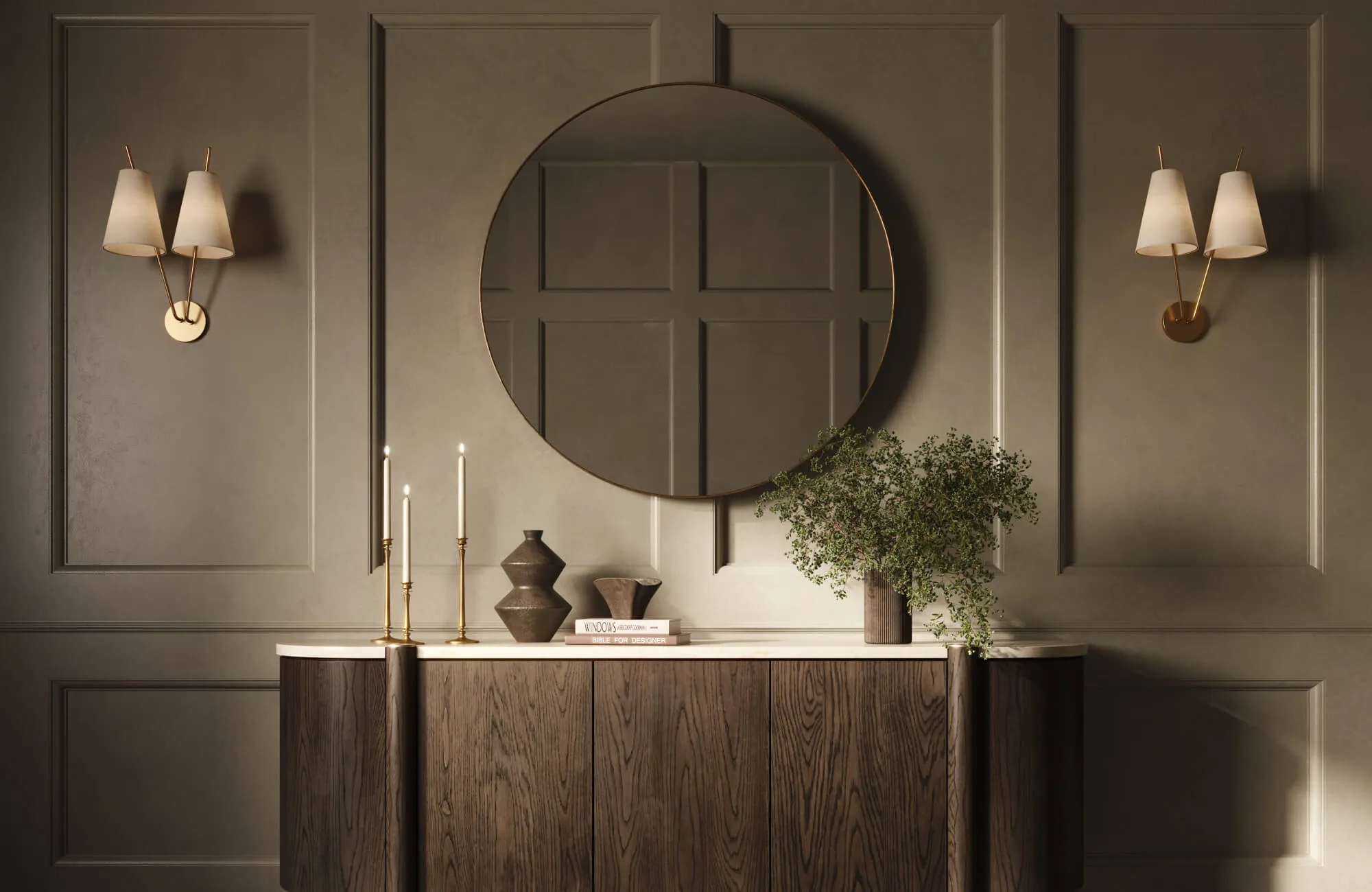 A large round mirror hangs above a dark wood console styled with candles, books, and greenery, set against paneled taupe walls with warm brass wall sconces.
