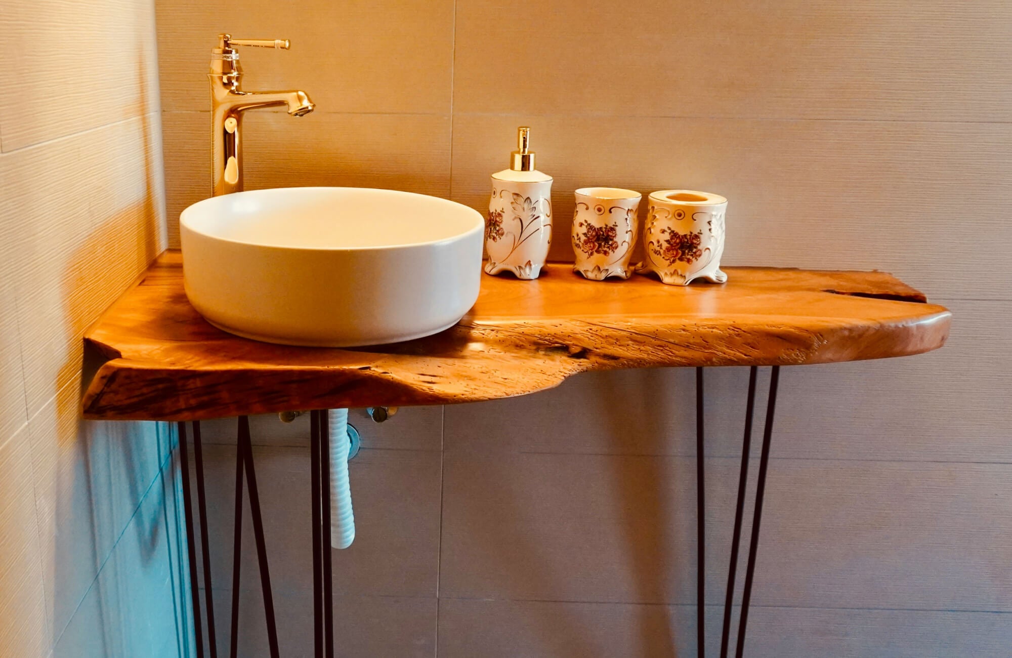 Rustic bathroom vanity with a live-edge wood countertop, round vessel sink, and warm metal fixtures.