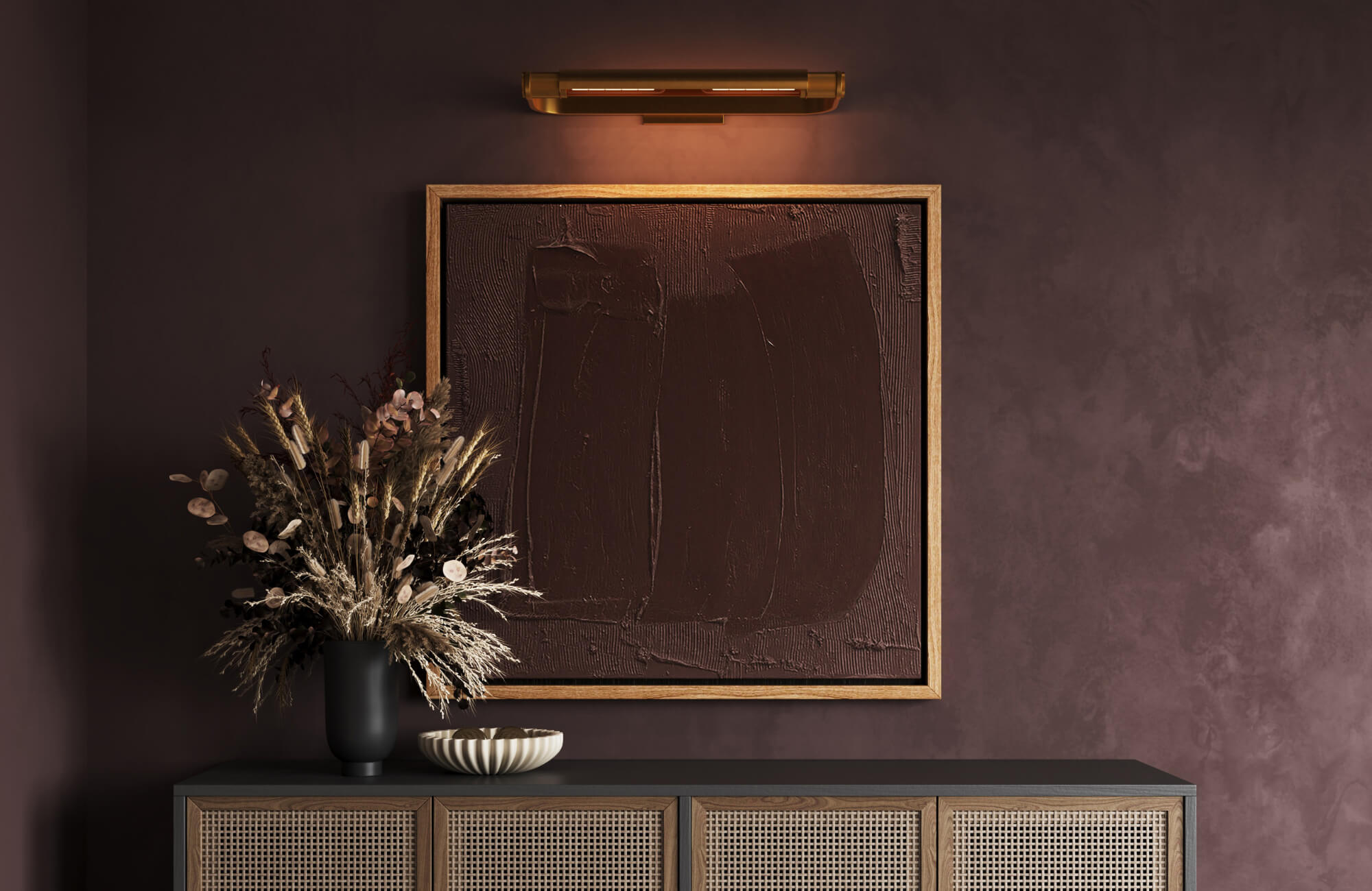 null A deep-toned entryway showcasing a textured monochrome artwork illuminated by a warm brass picture light above a rattan credenza.