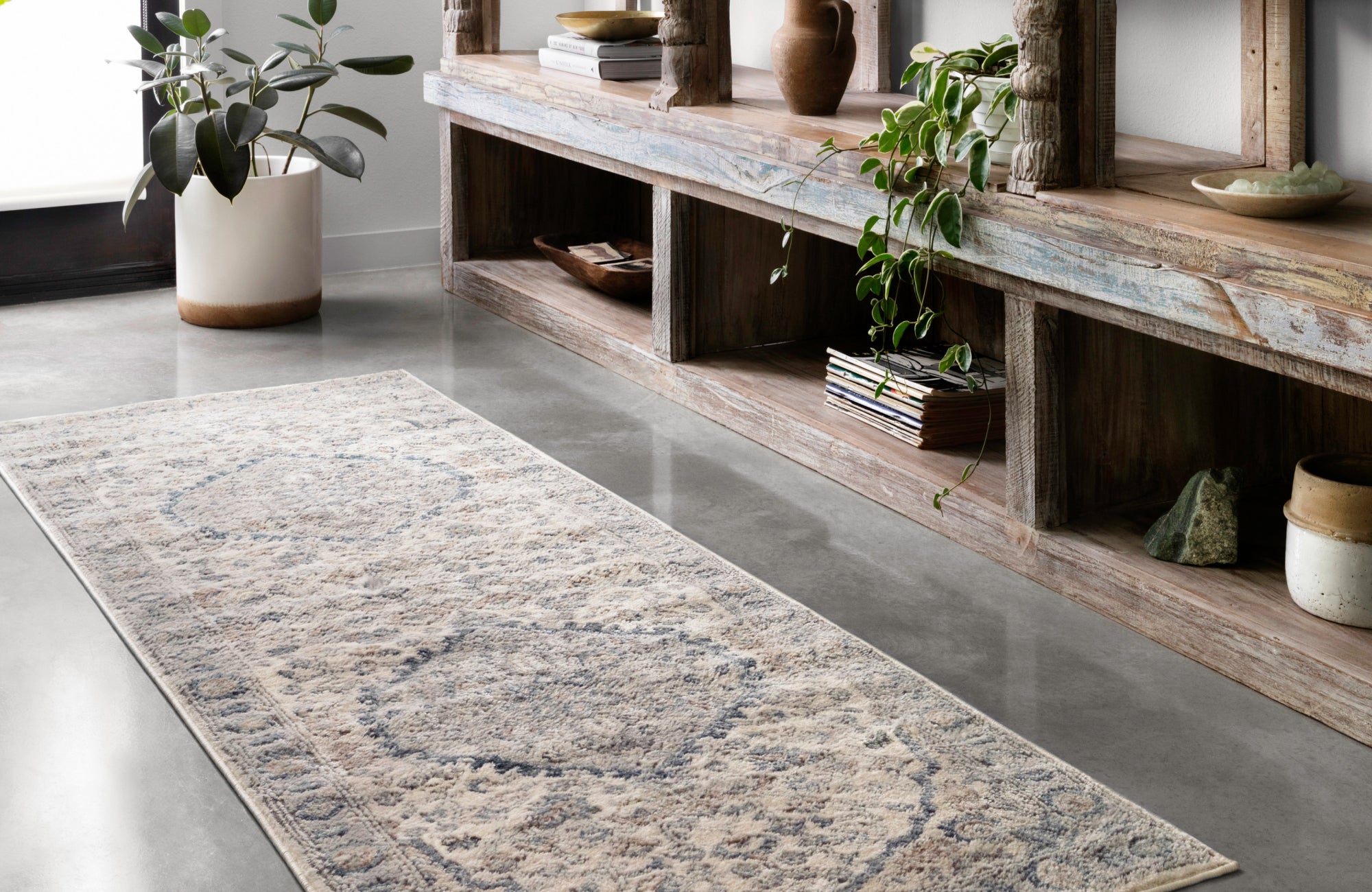 A hallway styled with rustic wood shelving and a light-toned runner rug that blends subtly with the concrete flooring for a seamless look.
