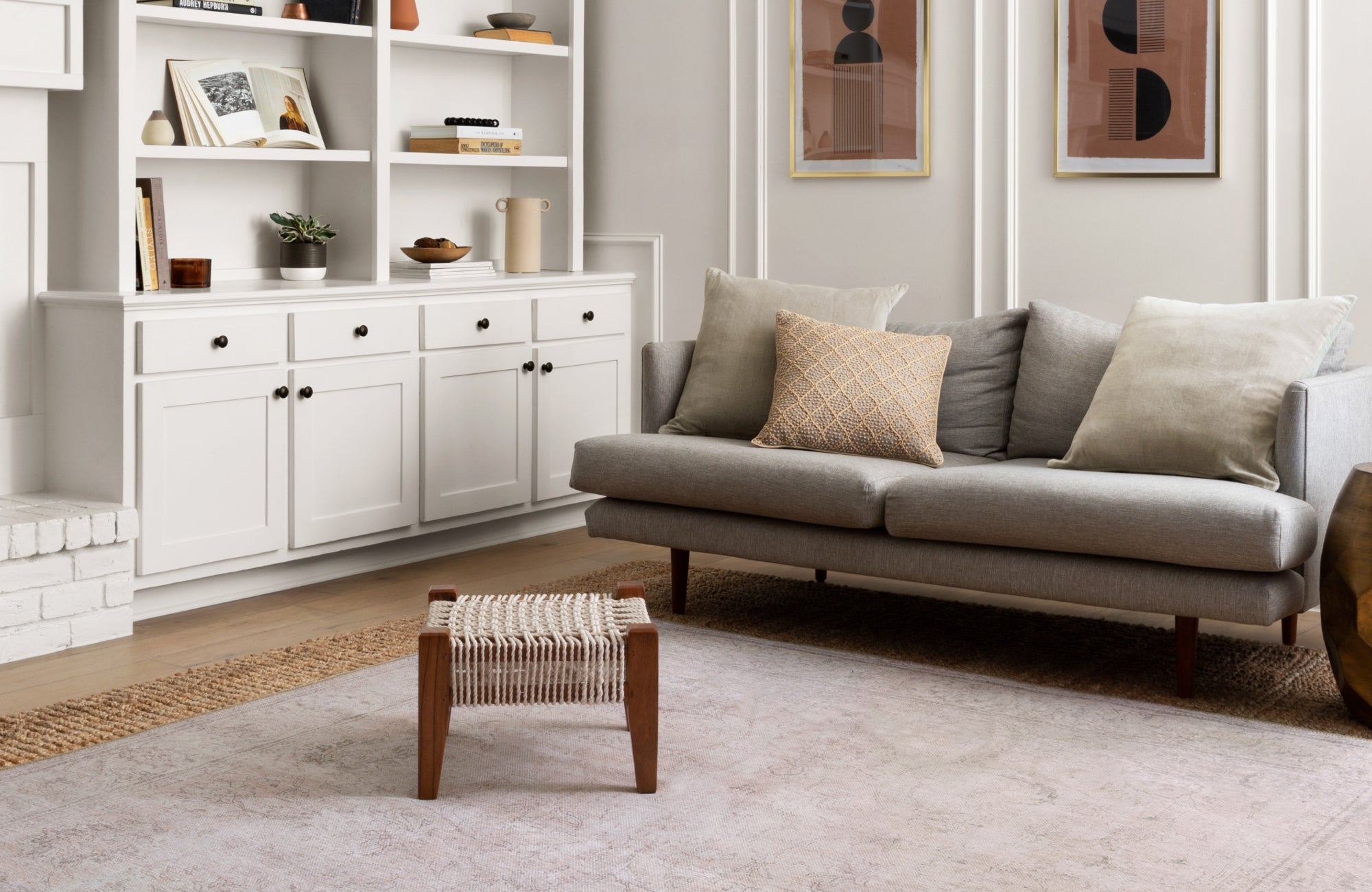 A Scandinavian-inspired living room with white paneling, modern decor, and a light-toned taupe rug that complements the clean, minimal palette.
