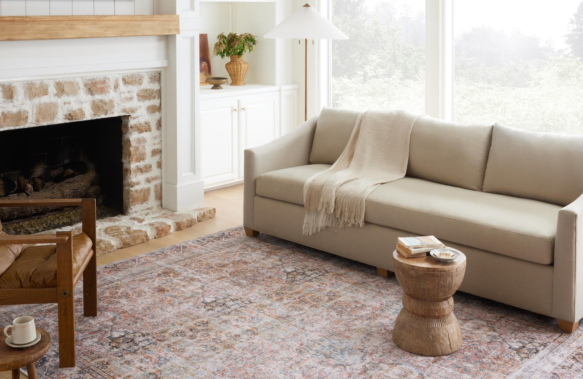 A bright, inviting living room with a beige sofa and a faded, warm-toned rug in light shades that adds texture and softness to the cozy setting.