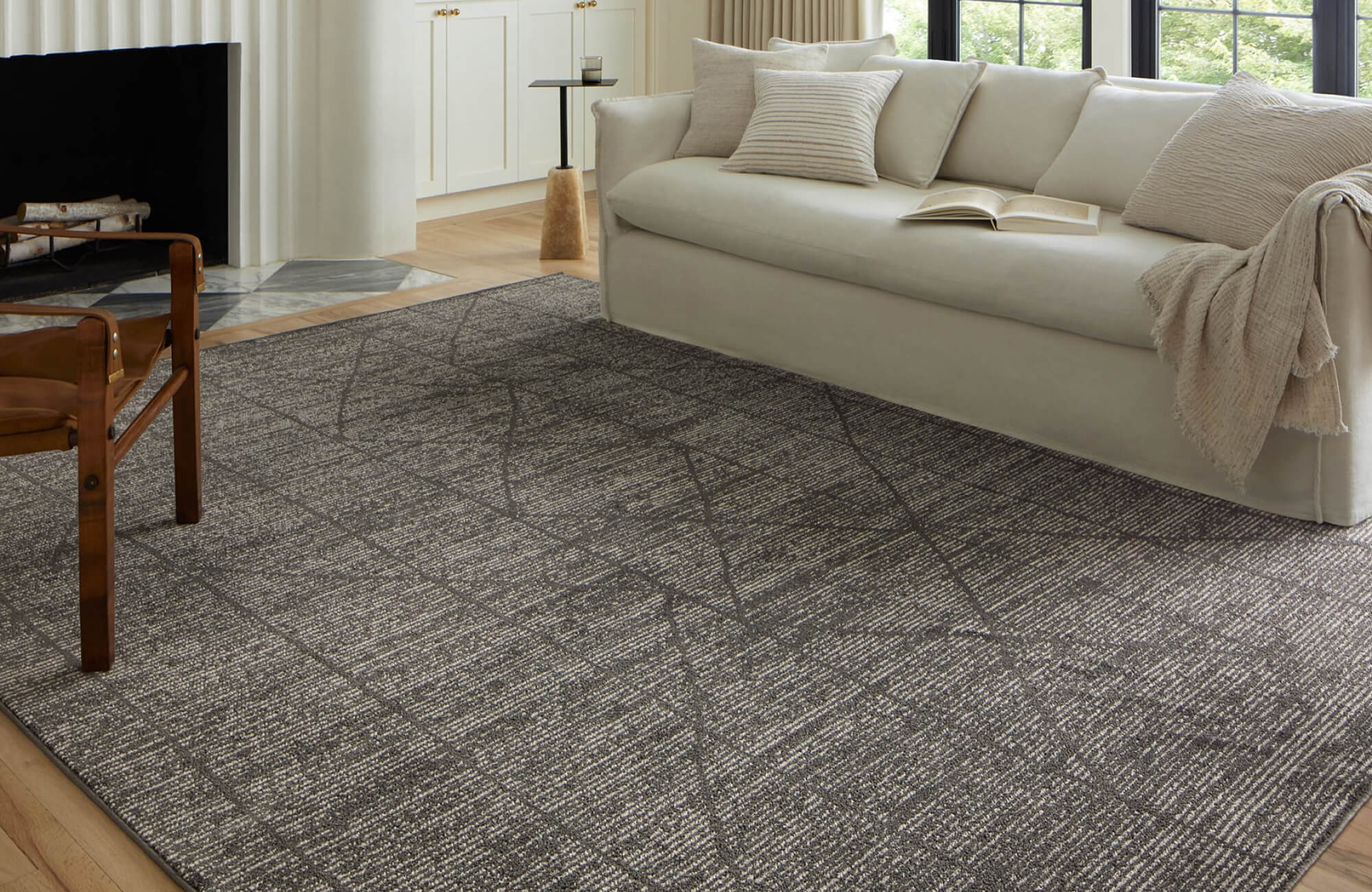 Modern living room with a textured charcoal area rug, cream sofa, and light wood flooring for a cozy, refined feel.