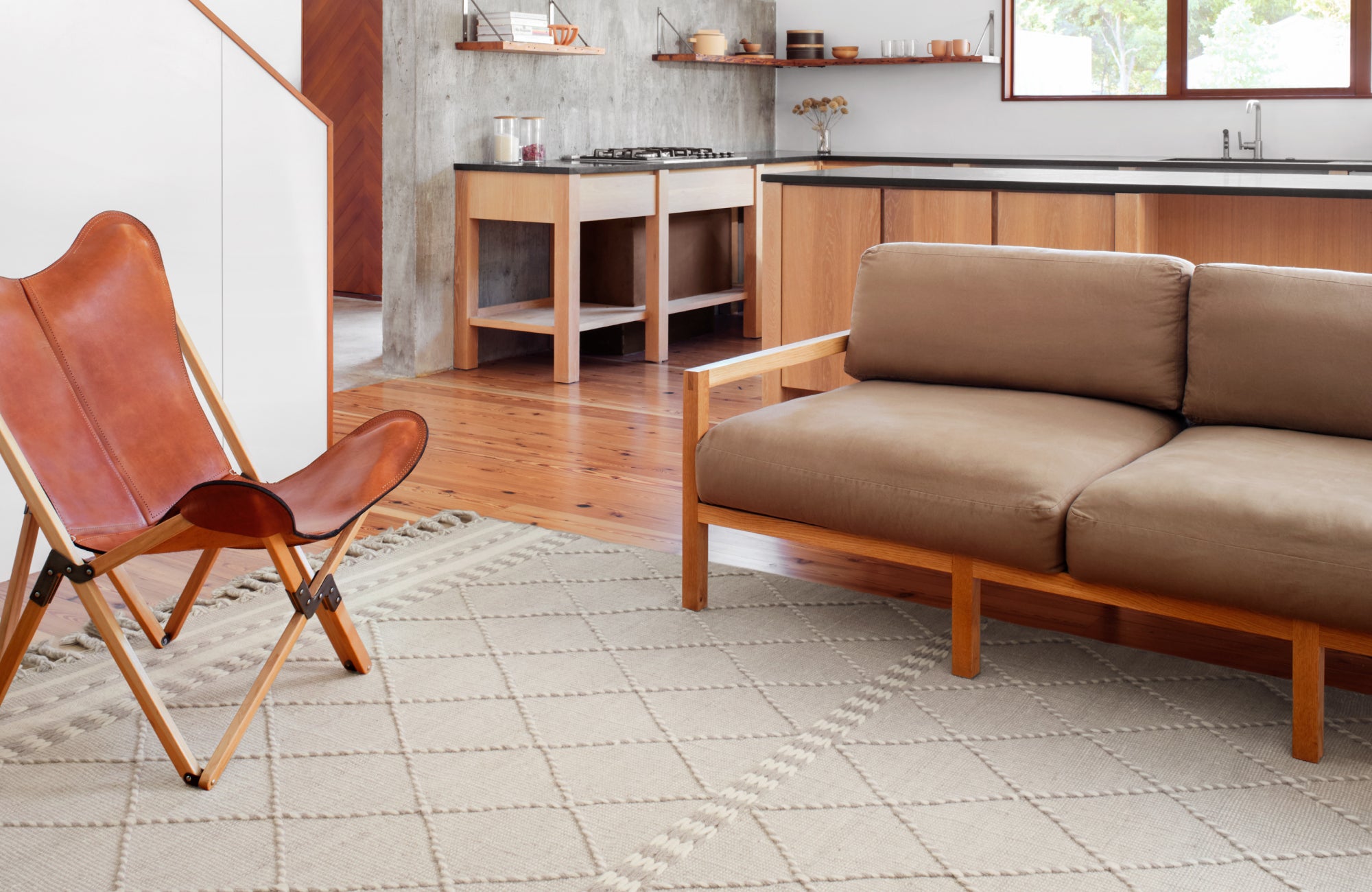Neutral diamond-patterned rug coordinates subtly with sofa and wall for a seamless, grounded look.