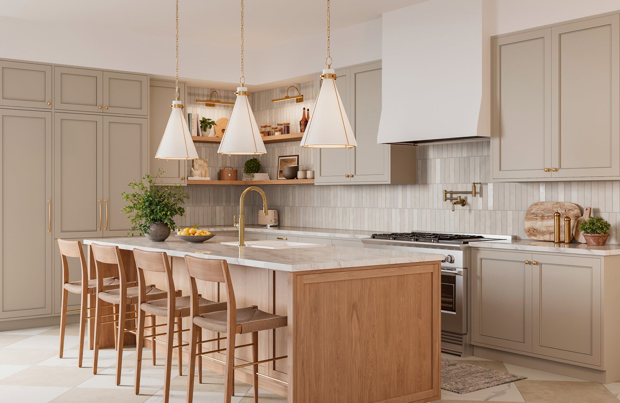 Pendant lights in brushed brass finish pair with a matching faucet in a light-toned kitchen with a wood island.