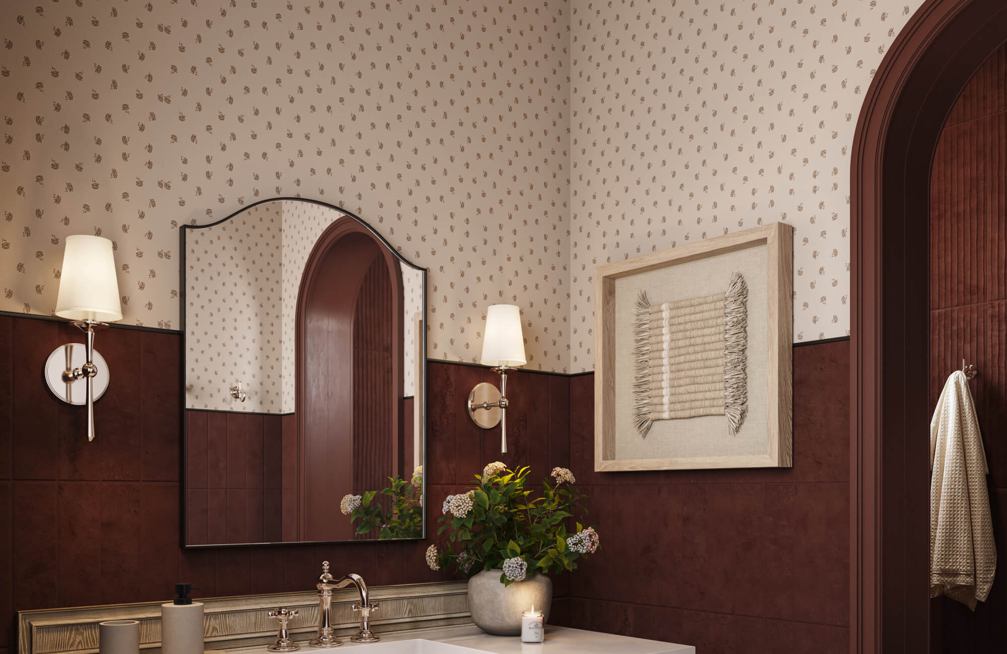 Elegant bathroom with warm brown wall tiles, arched mirror, wall art, brass fixtures, and delicate patterned wallpaper accents.