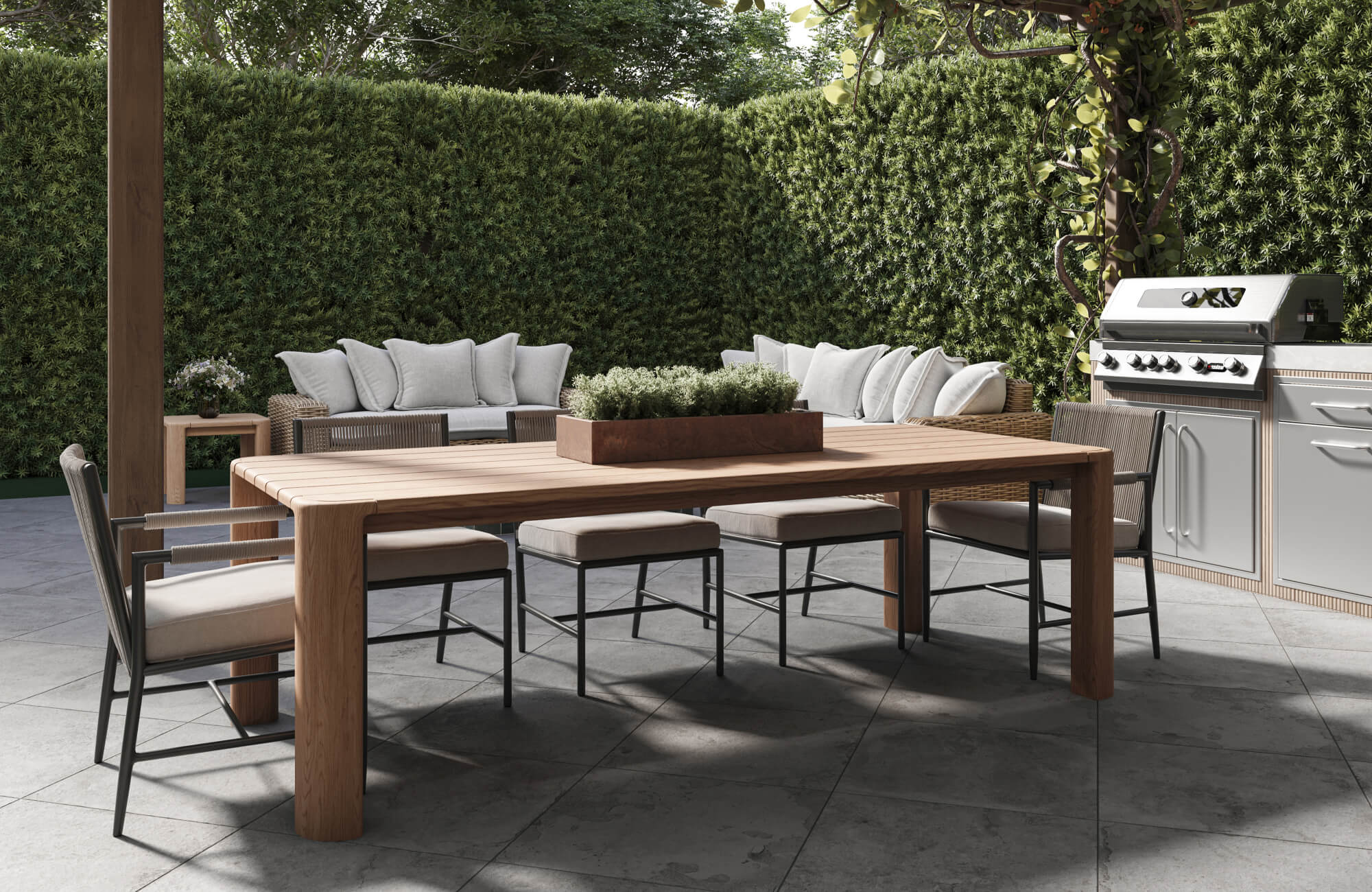 Large gray floor tiles create a sleek outdoor kitchen and dining area with a wood table, dining chairs, and greenery.