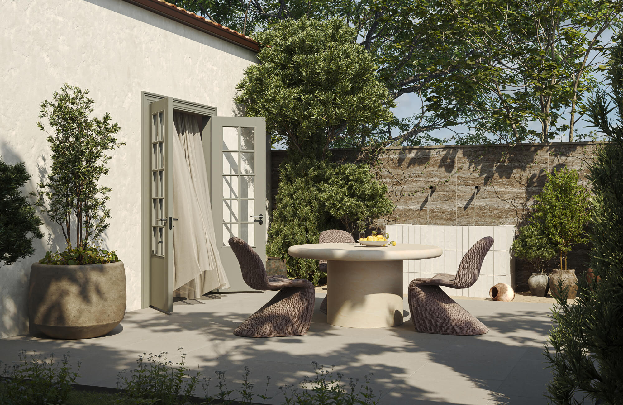 Serene garden dining nook with woven dining chairs, round dining table and soft Mediterranean greenery.
