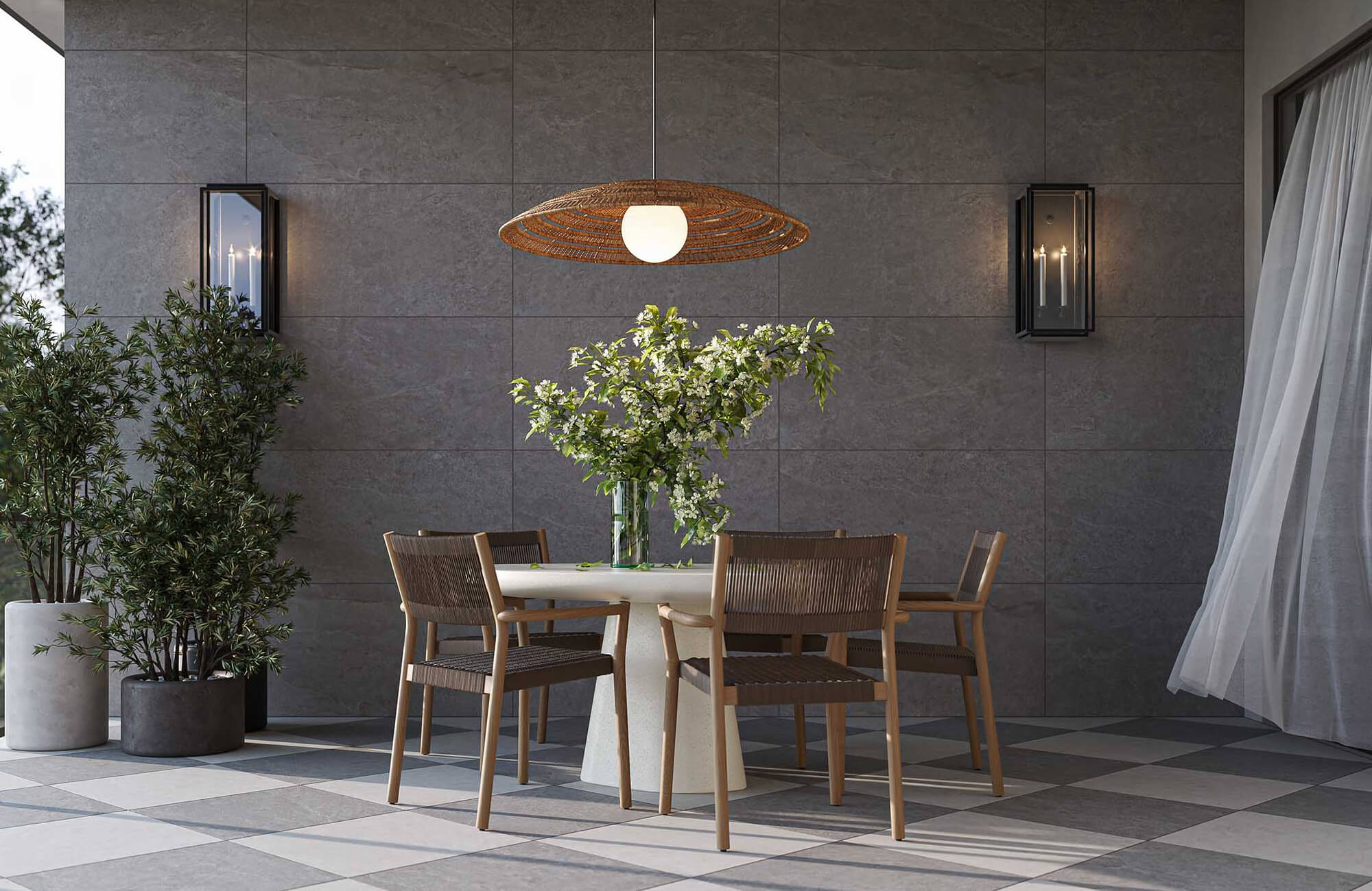 Refined outdoor dining space with a checkerboard tile flooring, round table, woven chairs, sconces, and a pendant light.