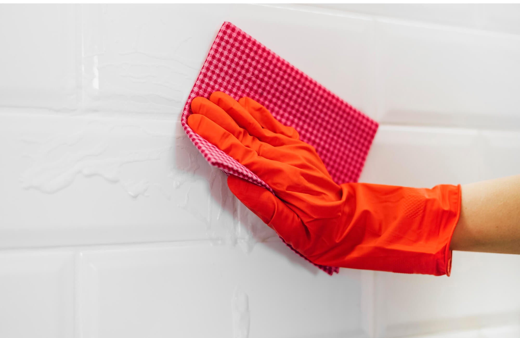 Smooth white shower tiles being wiped clean highlight how light surfaces reveal water spots and routine maintenance needs.