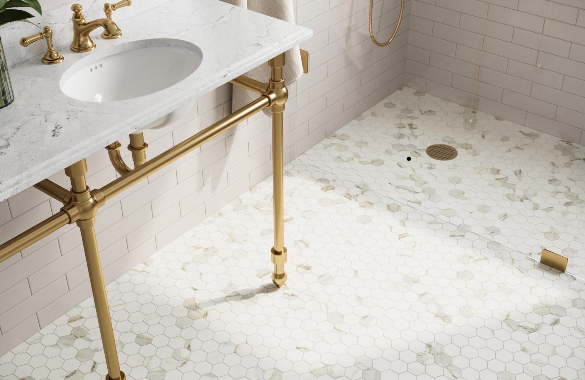 null White hexagon tile bathroom floor with subtle marble accents beneath a brass vanity and walk-in shower reflects light throughout the space, helping a compact layout feel more expansive.