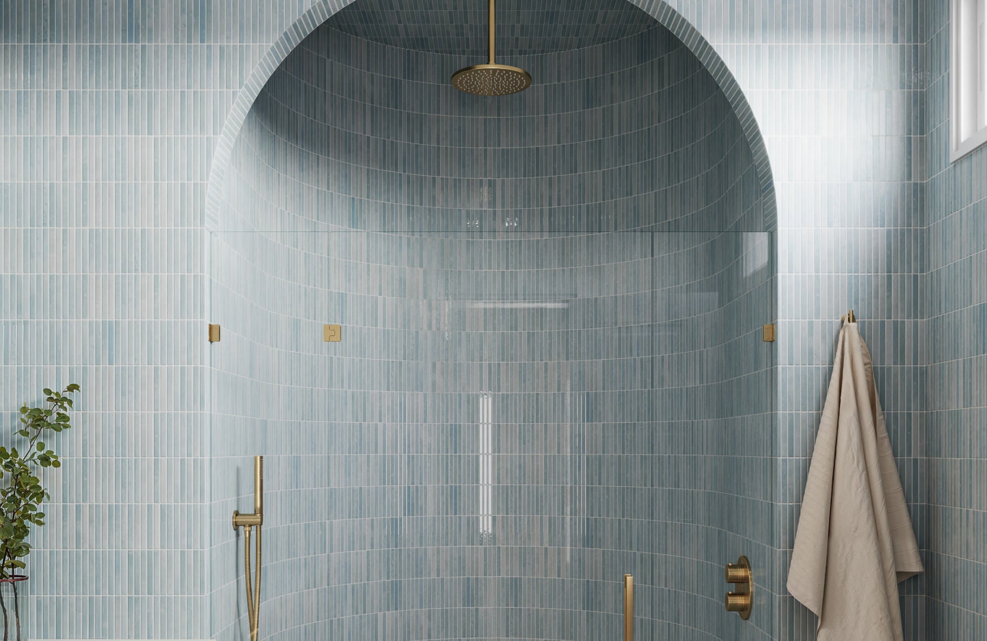 null Light blue vertically stacked tiles wrap this arched shower, reflecting soft light and creating a calm, open atmosphere that makes the space feel taller.