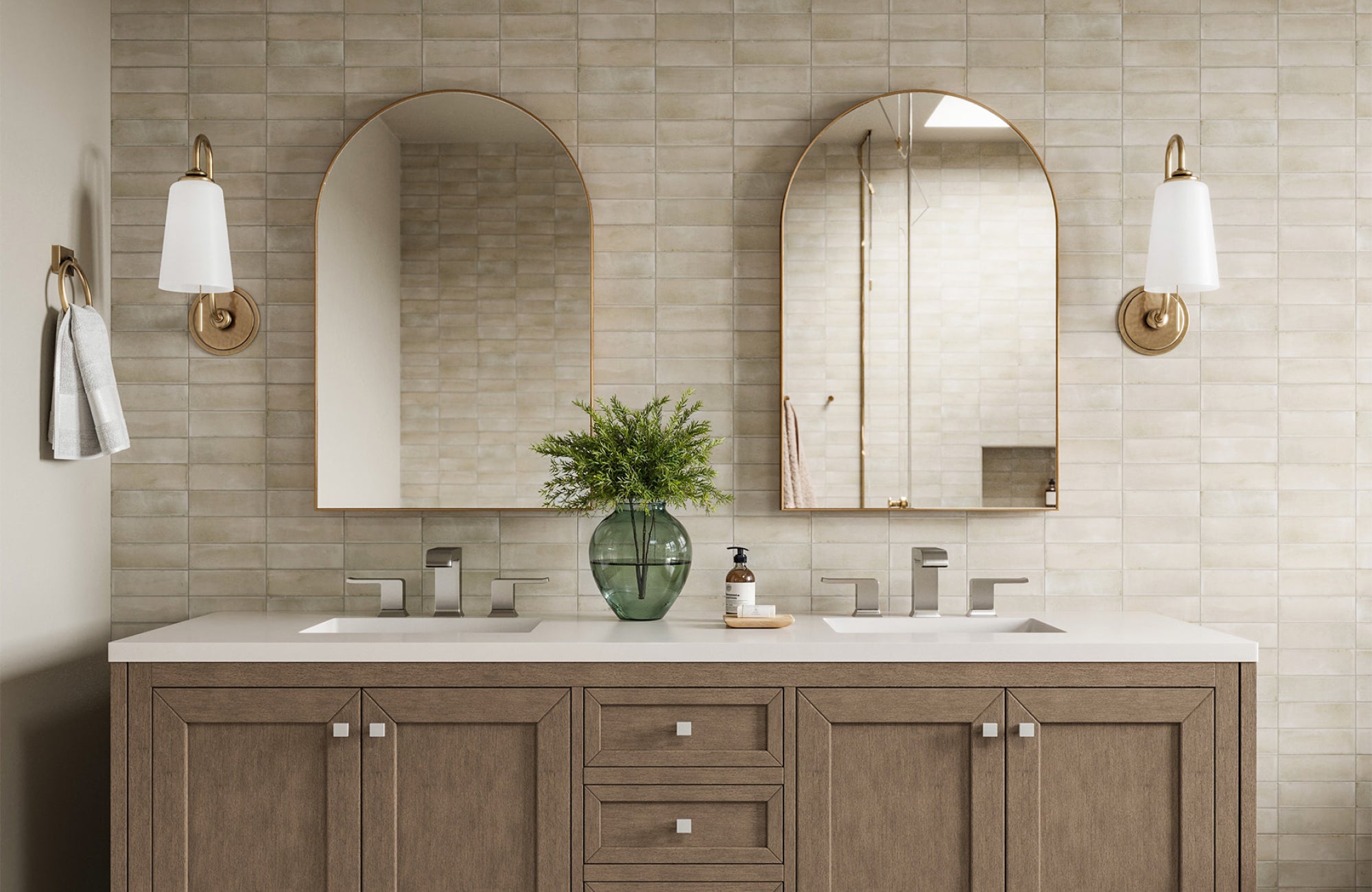 Aged brass wall sconces with white shades sit beside arched mirrors in a warm, neutral-toned double vanity setup.