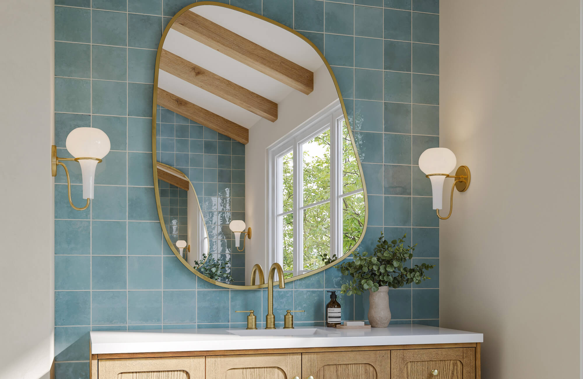 Organic-shaped framed brass mirror over turquoise tile backsplash, paired with brass fixtures and light oak vanity.
