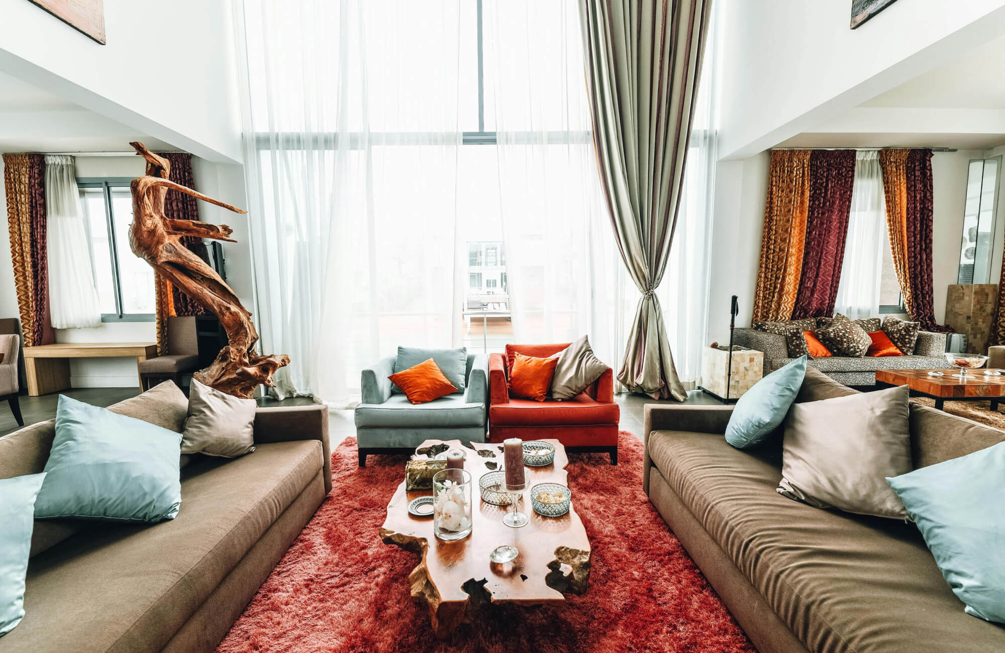 null Spacious living room with neutral tile flooring, plush sofas with colorful decorative pillows, and a rustic wood coffee table.
