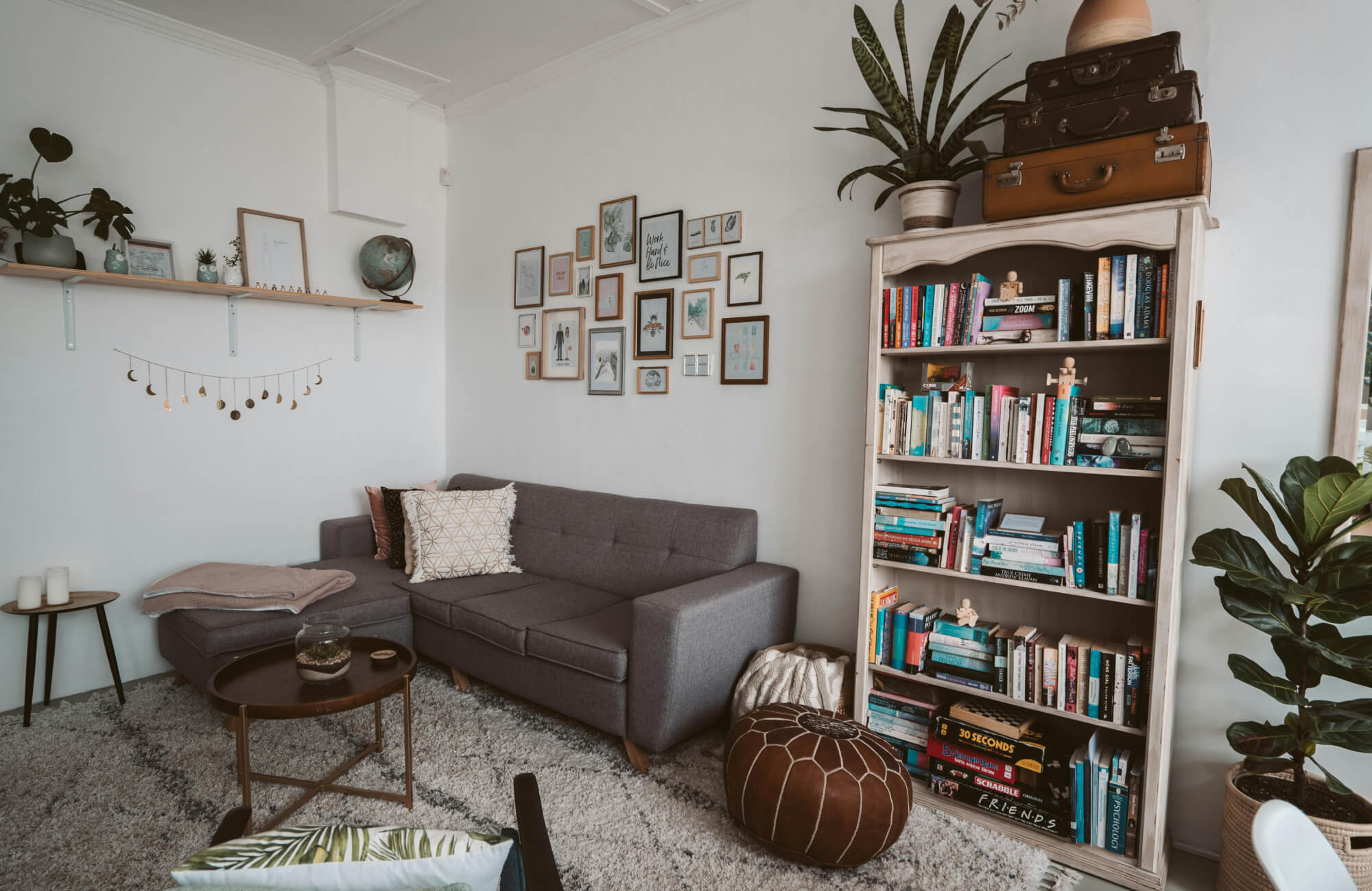 null Cozy reading nook with soft gray tile flooring, modern sofa with decorative pillows, and a styled bookshelf wall.