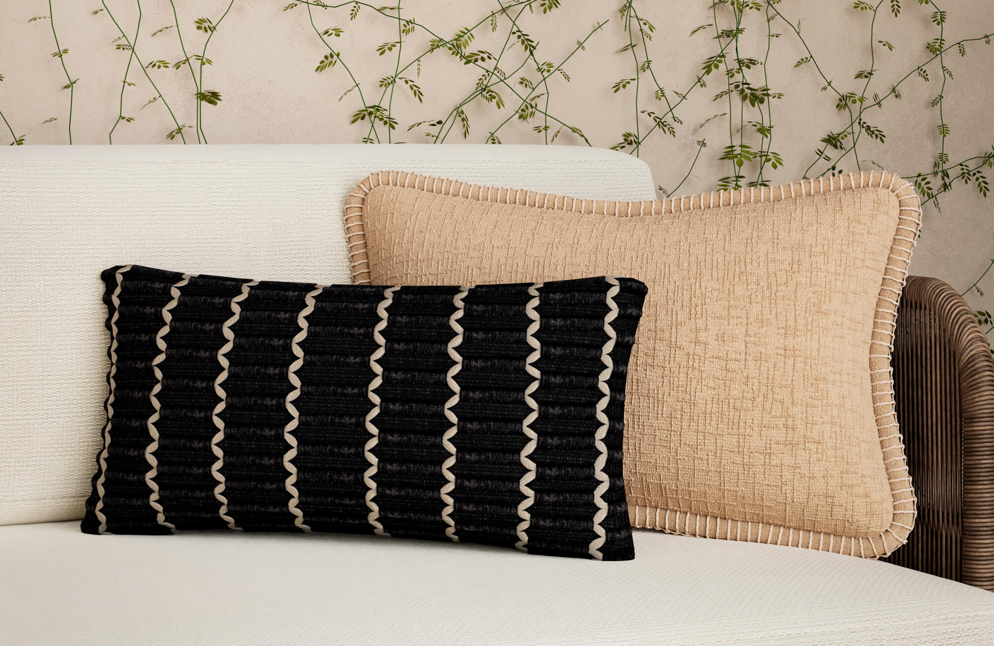 Close-up of a white outdoor sofa with a black patterned lumbar pillow and a beige textured square pillow against a wall with trailing greenery.