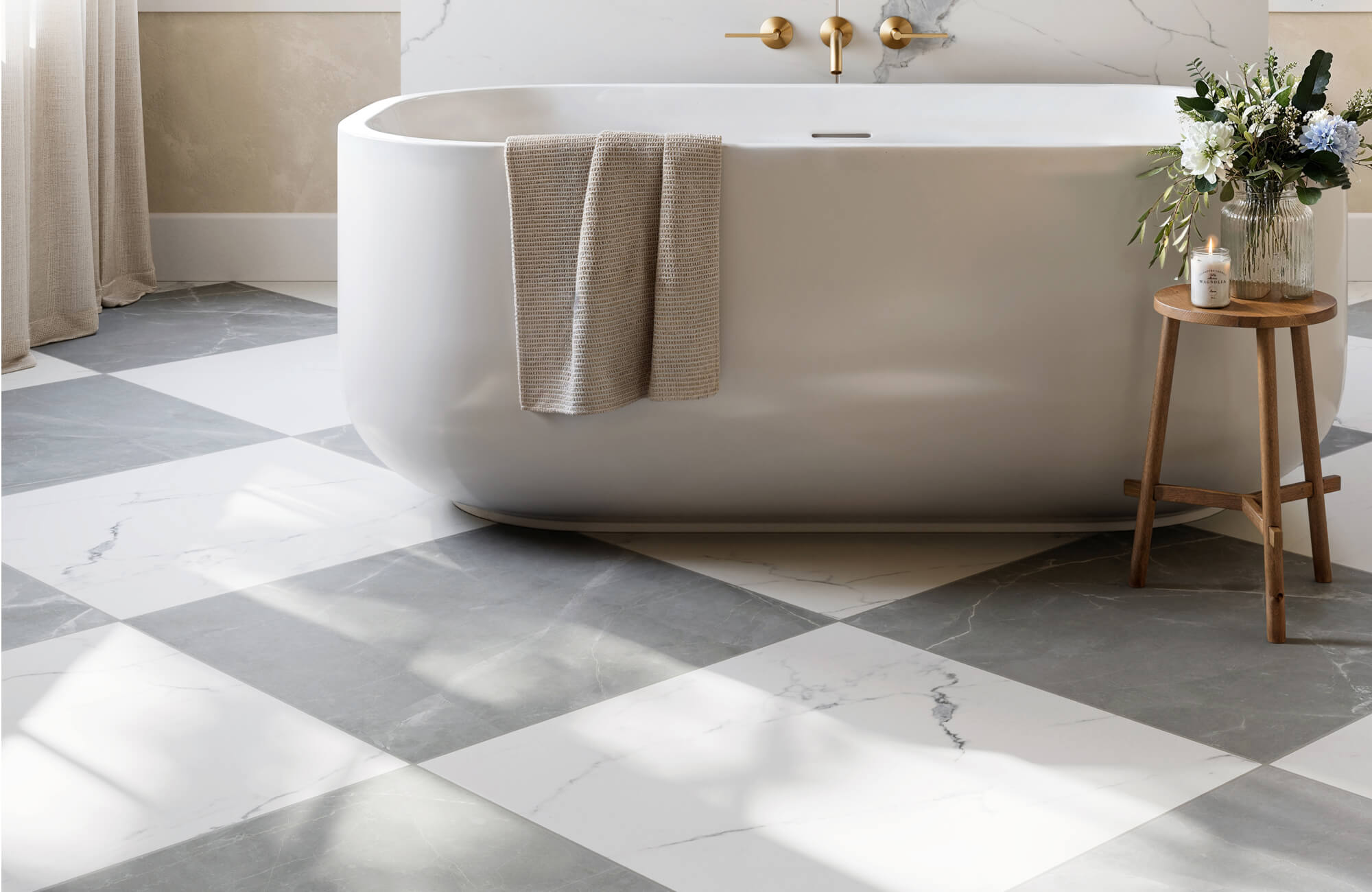 Contemporary bathroom featuring a freestanding tub paired with large format gray and white marble look floor tiles in a checkerboard pattern, creating a refined and spacious aesthetic with elegant contrast.