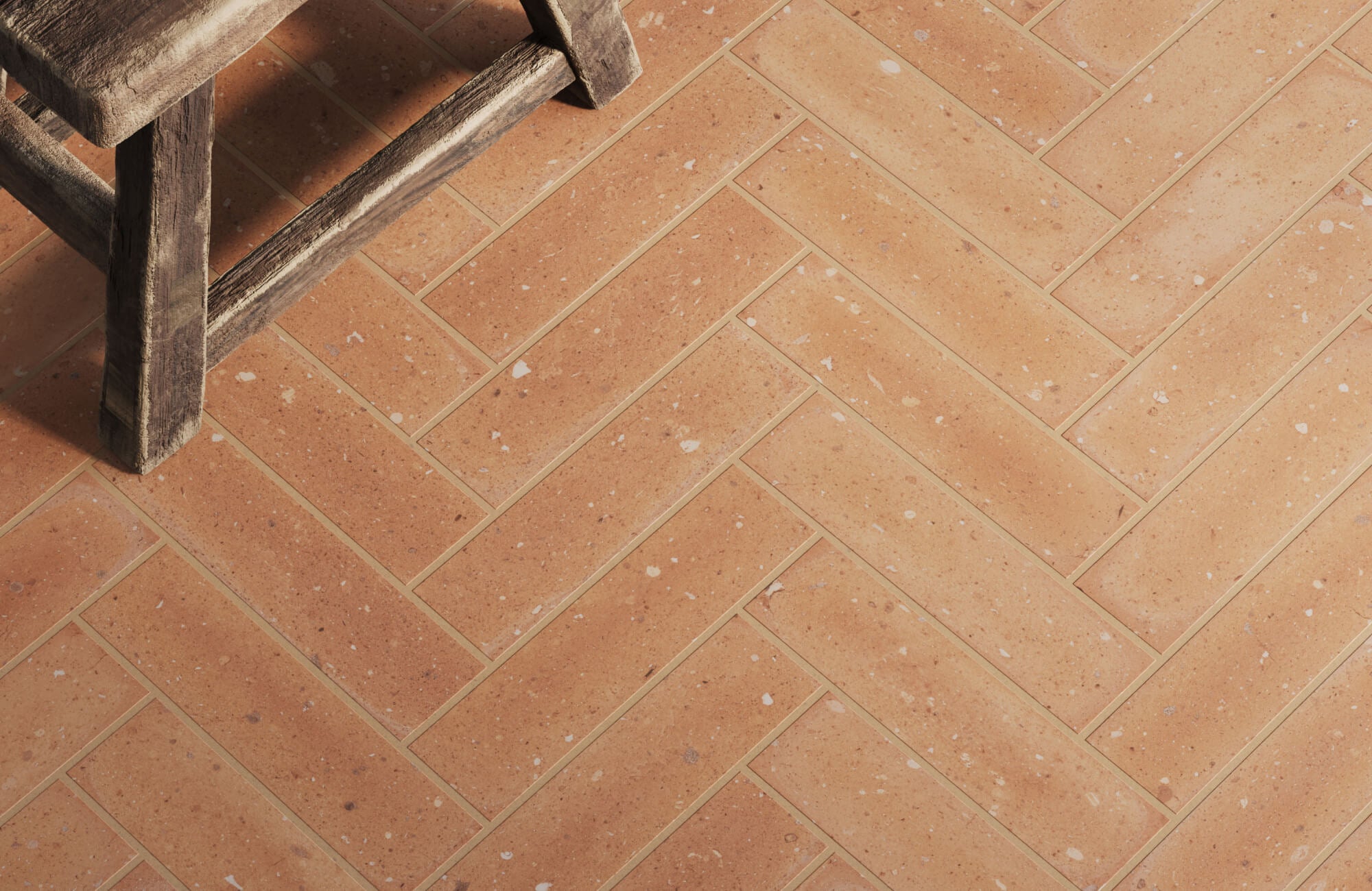 Warm bathroom floor featuring terracotta-style tiles arranged in a herringbone pattern, highlighting earthy tones and natural texture for a rustic, handcrafted charm.