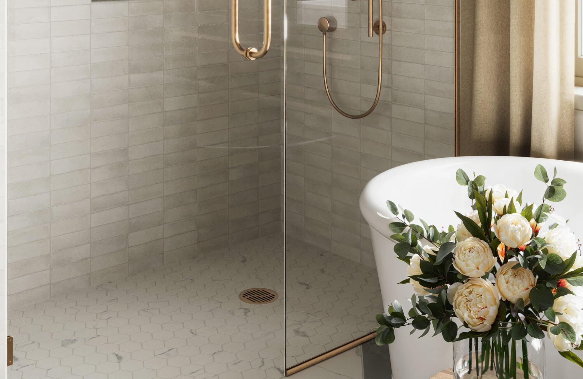 Luxurious bathroom featuring a glass-enclosed shower with marble look hexagon floor tiles and soft gray wall tiles, accented by brushed gold fixtures and a freestanding tub for an elegant, spa-like ambiance.