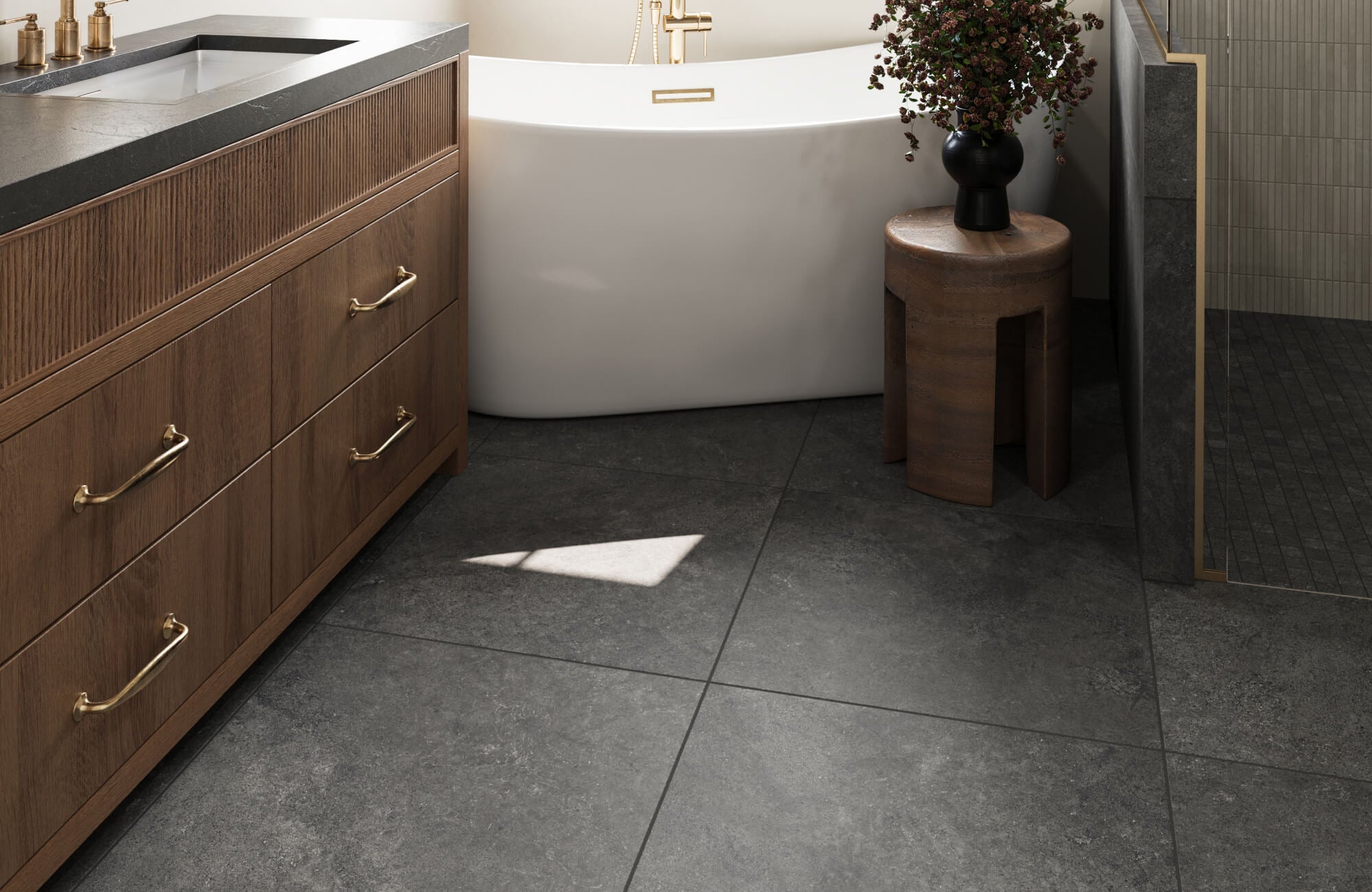 Sophisticated bathroom featuring dark gray stone look floor tiles paired with a rich wood vanity and brass accents, creating a warm yet contemporary atmosphere with luxurious contrast.