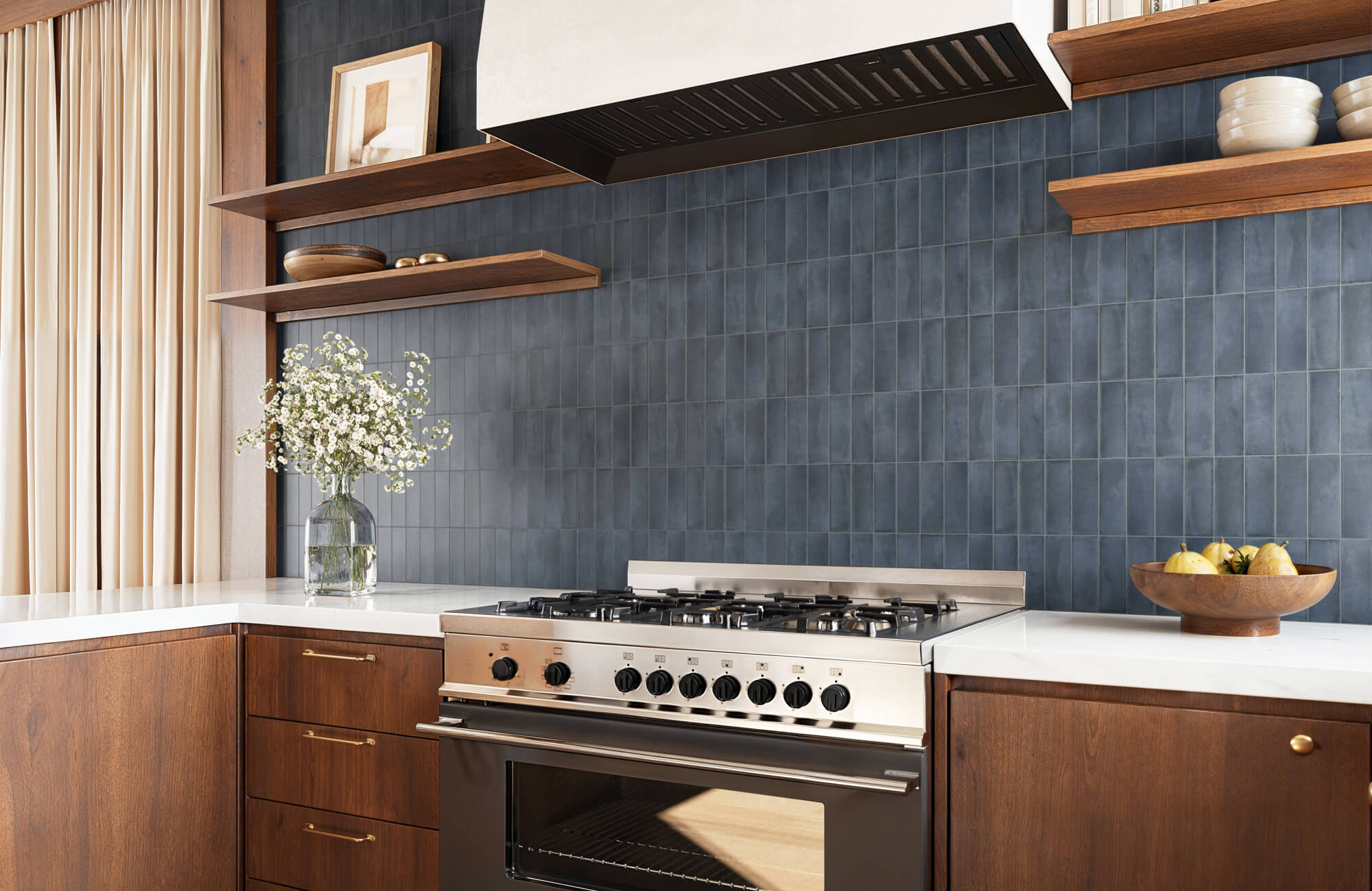 null A vertical stacked pattern of blue subway tiles lines the kitchen backsplash, adding a clean backdrop to the range and shelves.