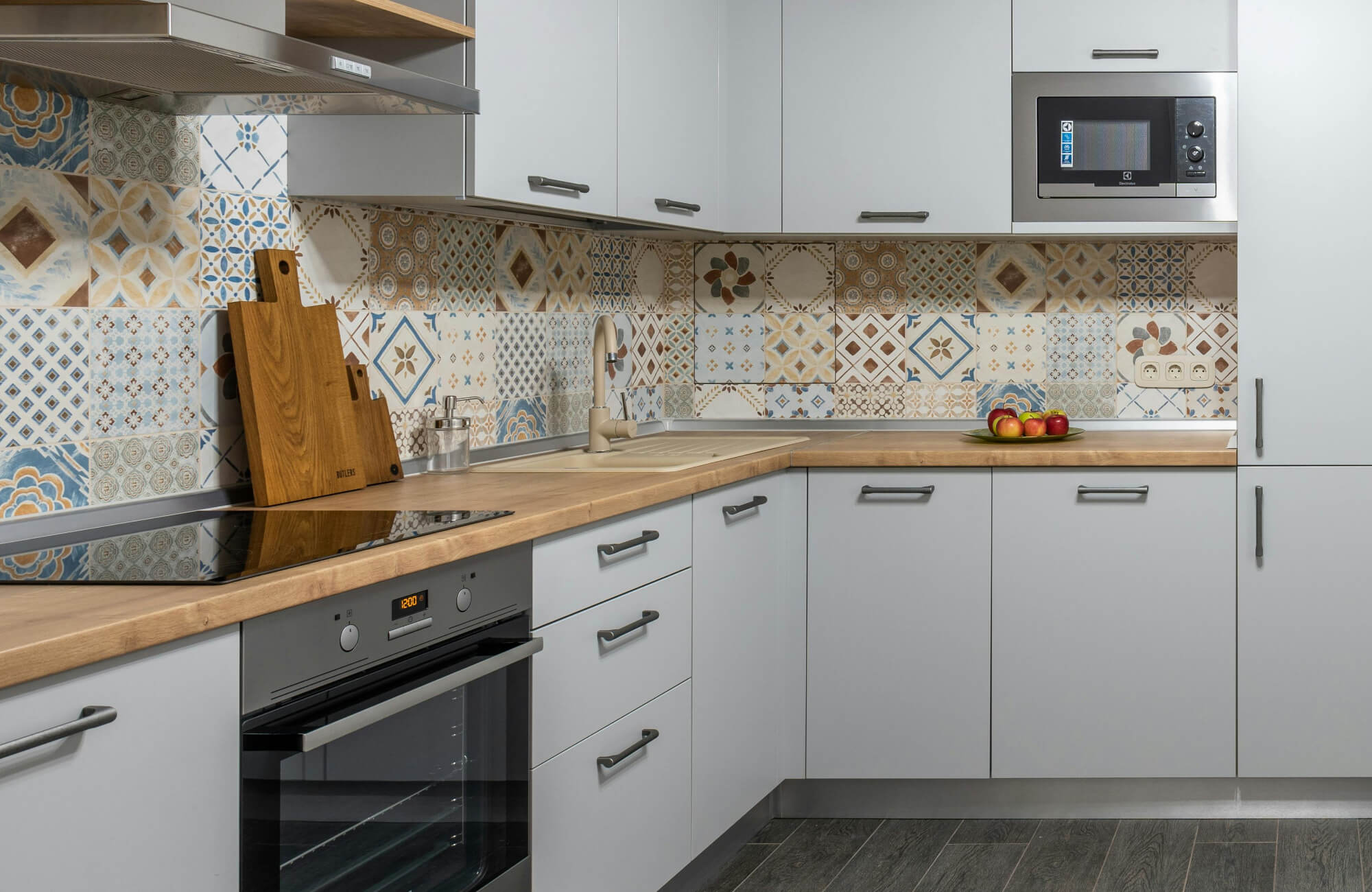 null Modern kitchen with light grey cabinets and a vibrant patterned cement tile backsplash in blue, beige, and terracotta.