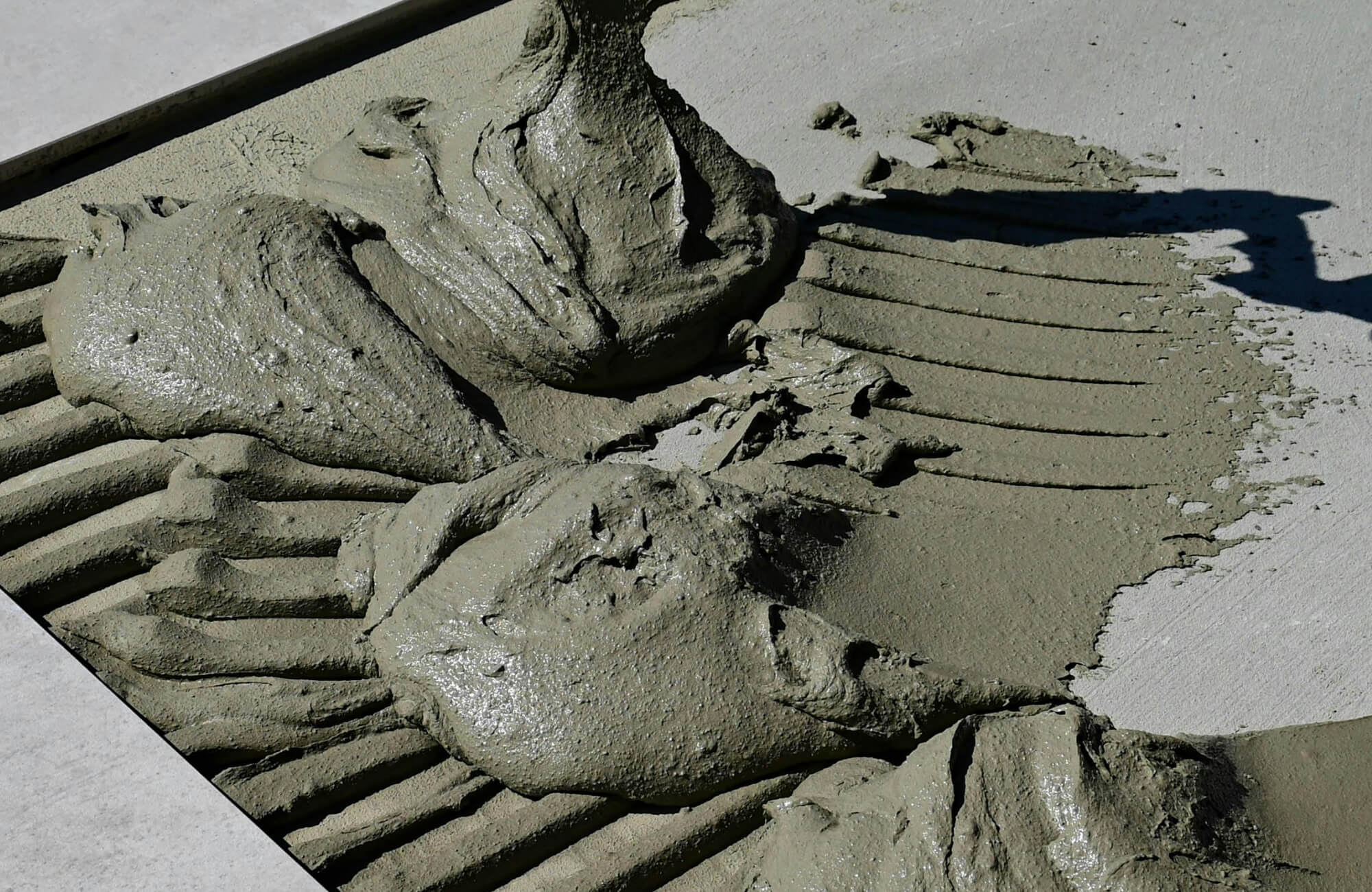 null Close-up of freshly applied mortar being spread over a concrete surface, showcasing its thick, textured consistency and ridged pattern ready for tile installation.