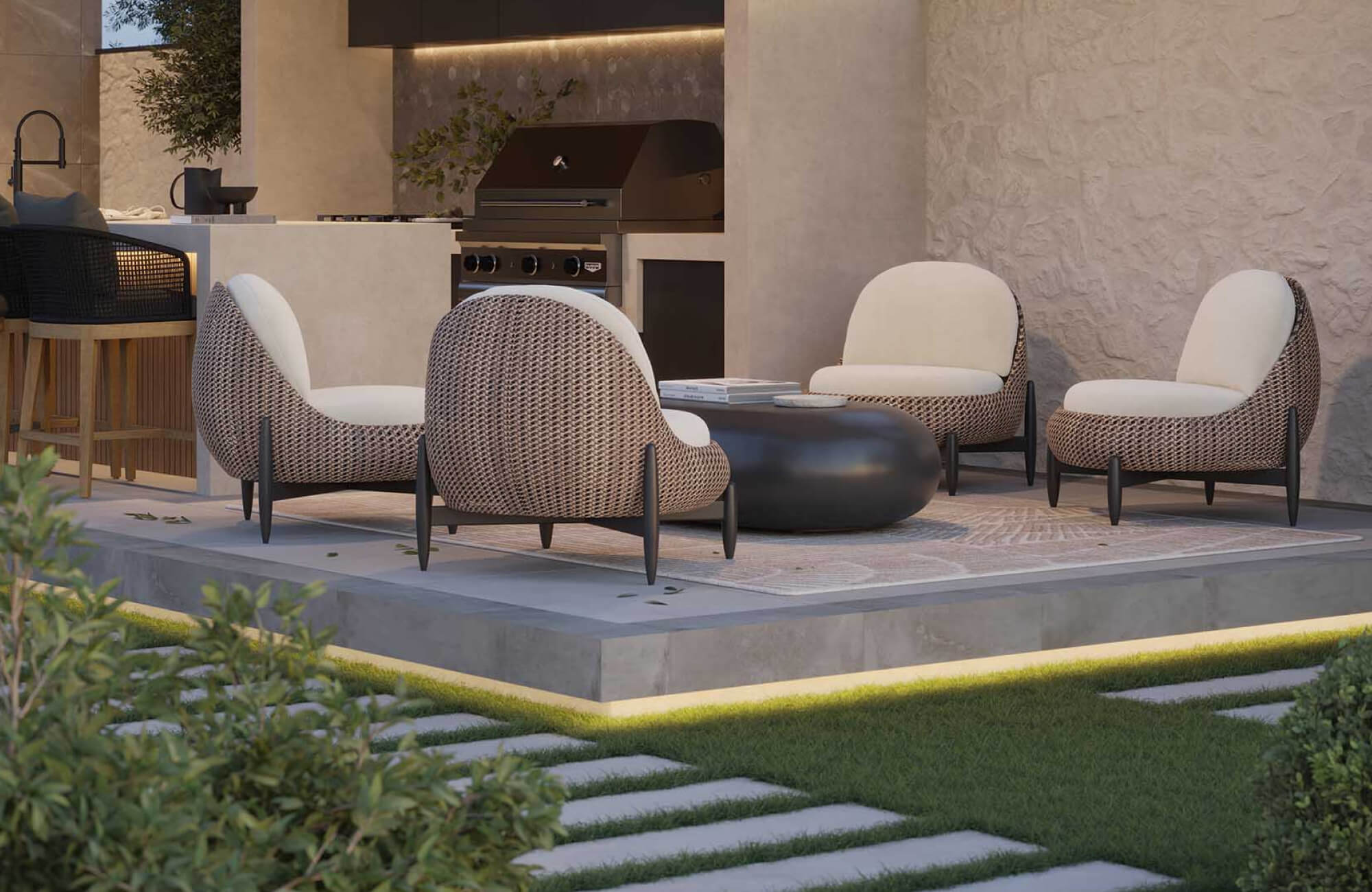 null Contemporary outdoor lounge area with curved woven chairs and a dark round coffee table set on a raised patio beside a modern outdoor kitchen.