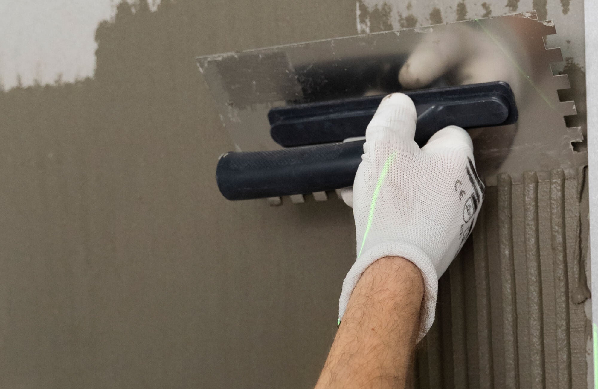 null Close-up of a craftsman applying thinset mortar with a notched trowel, creating precise ridges for secure and even tile installation.