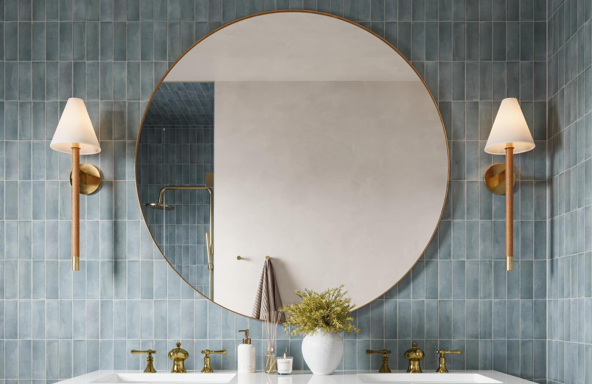 null Elegant bathroom with blue vertical tiles, large round mirror, brass fixtures, and soft cone sconces flanking the vanity.