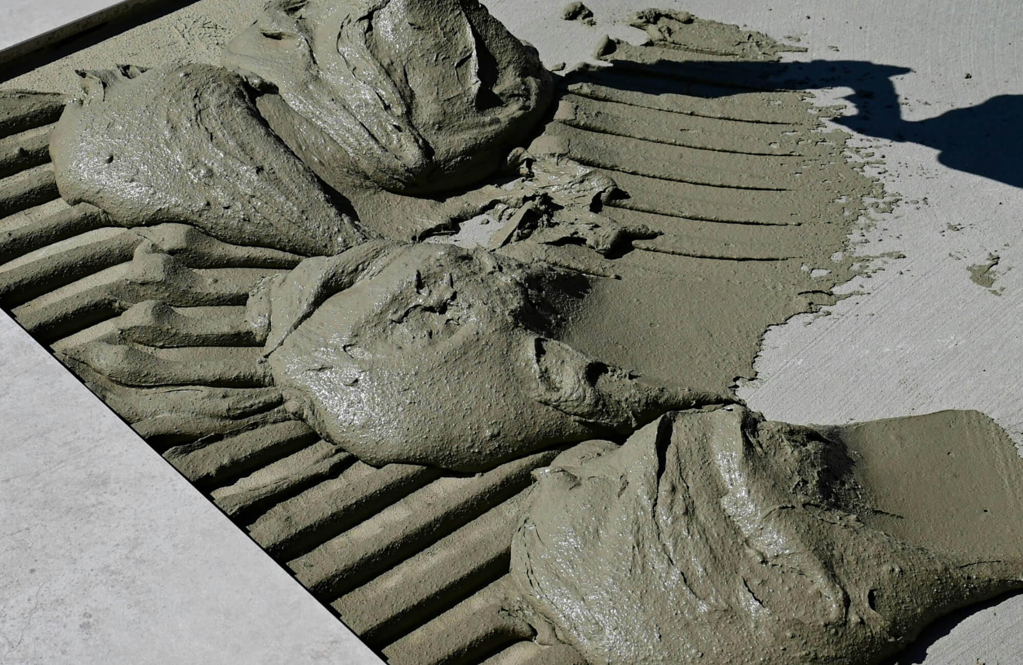 null Close-up view of freshly applied mortar with notched trowel lines, showcasing its smooth, wet texture and precision preparation for tile or paver installation.