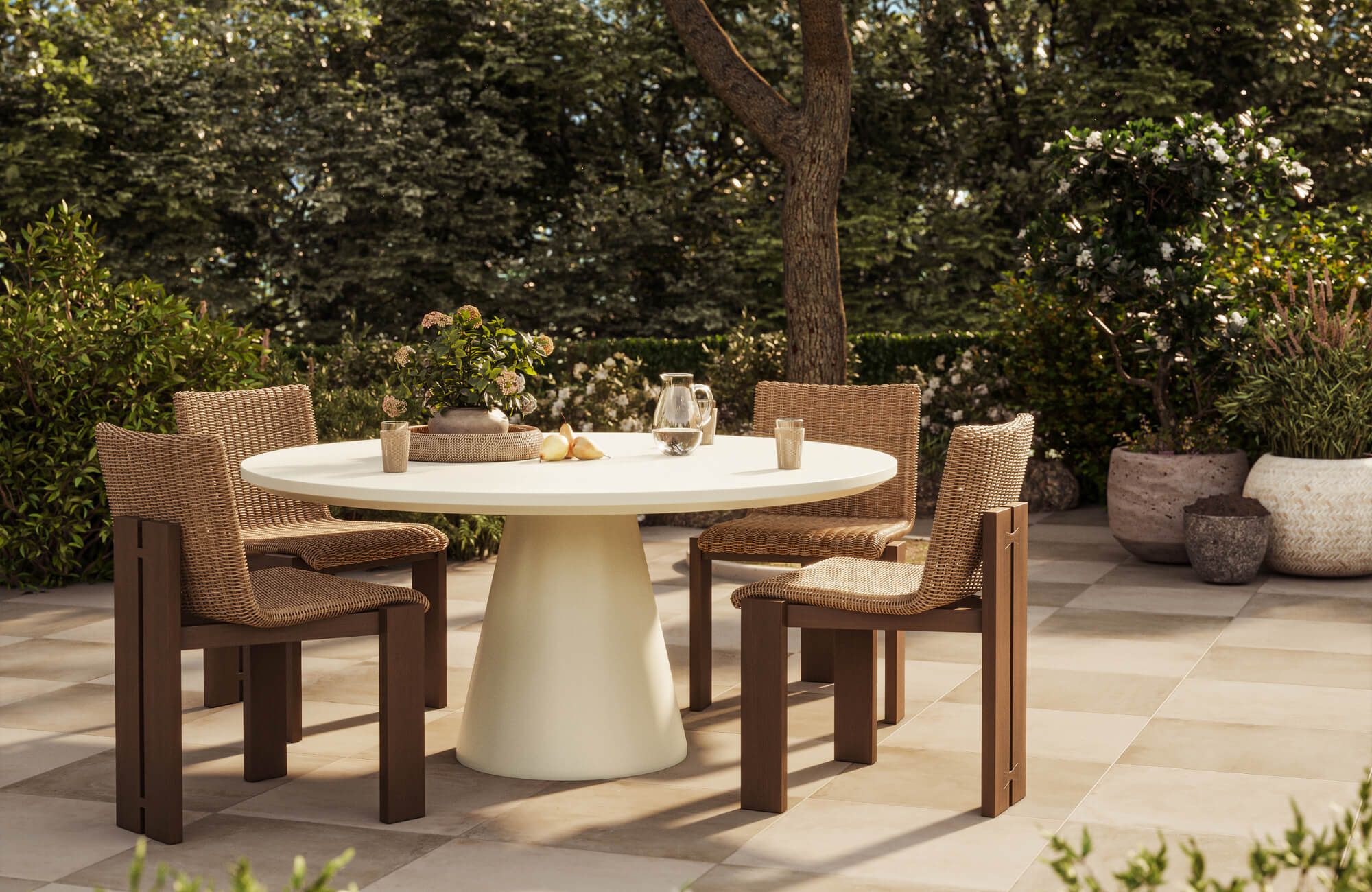 null Outdoor dining area with woven wood chairs, round pedestal table, and landscaped greenery surrounding tiled patio floors outside.