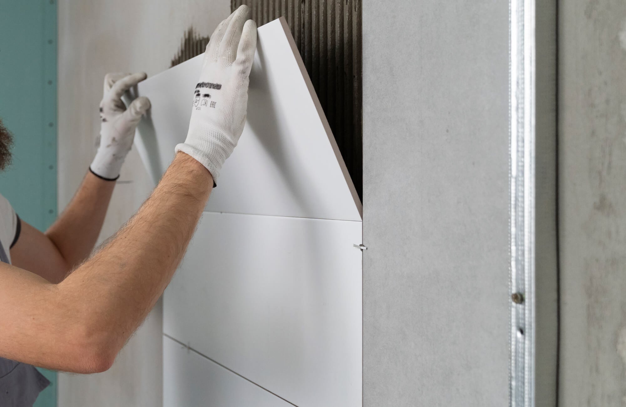 Installer carefully places a large-format ceramic tile over adhesive lines, guided by a precision laser for flawless alignment.
