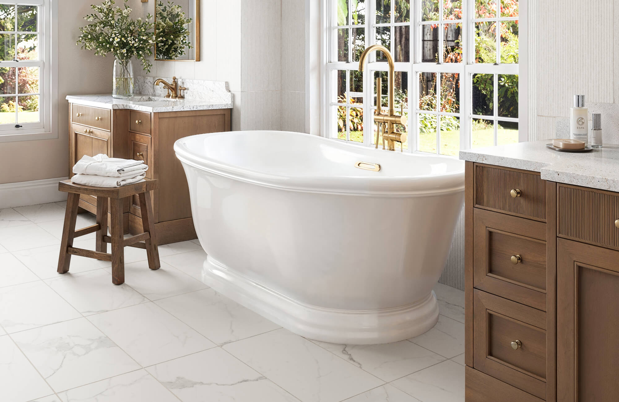 null Bright bathroom with white marble-look floor tiles, paired with a wood vanity and brass fixtures for a classic neutral tile design.