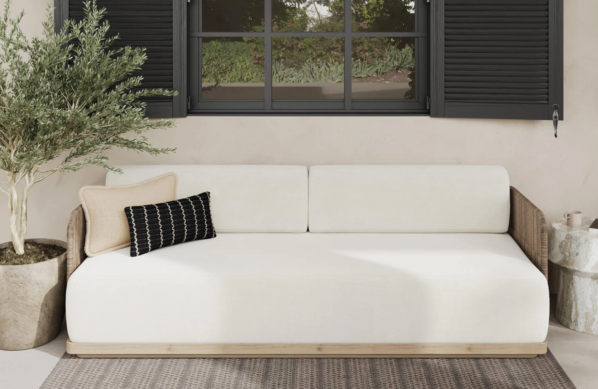 Serene outdoor lounge with beige floor tiles, cream sofa, and decorative pillows beneath black shutters.