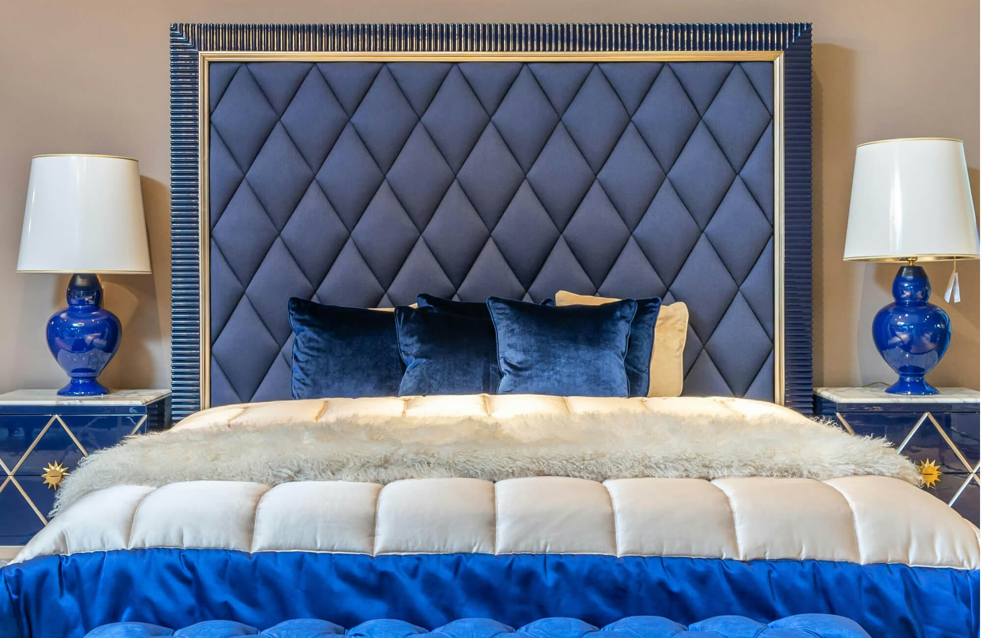 null Luxurious bedroom with tufted navy headboard, velvet decorative pillows, and bold blue accent furnishings.