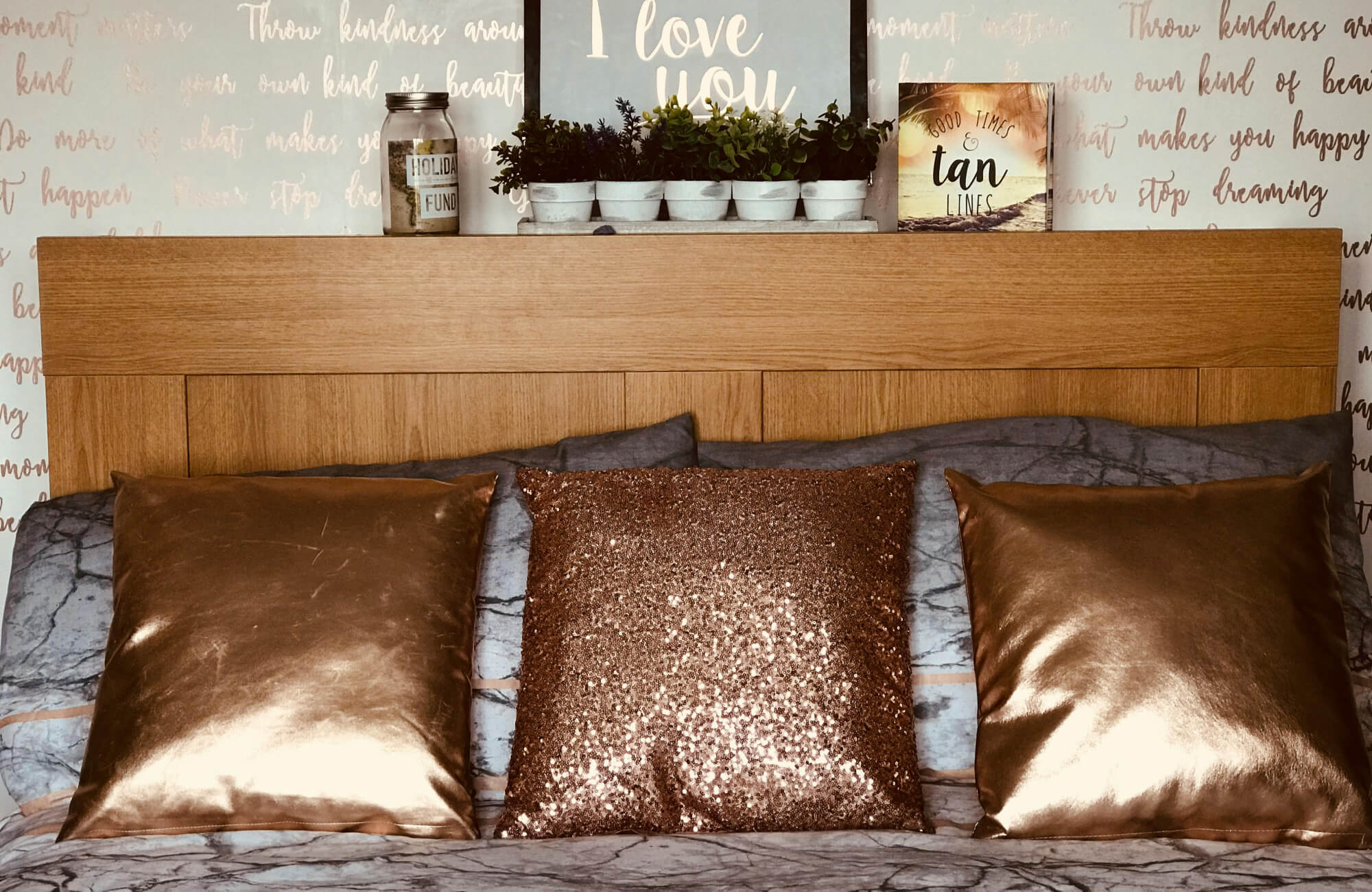 null Cozy bedroom with wood headboard, metallic decorative pillows, and scripted accent wall with “I love you” art.