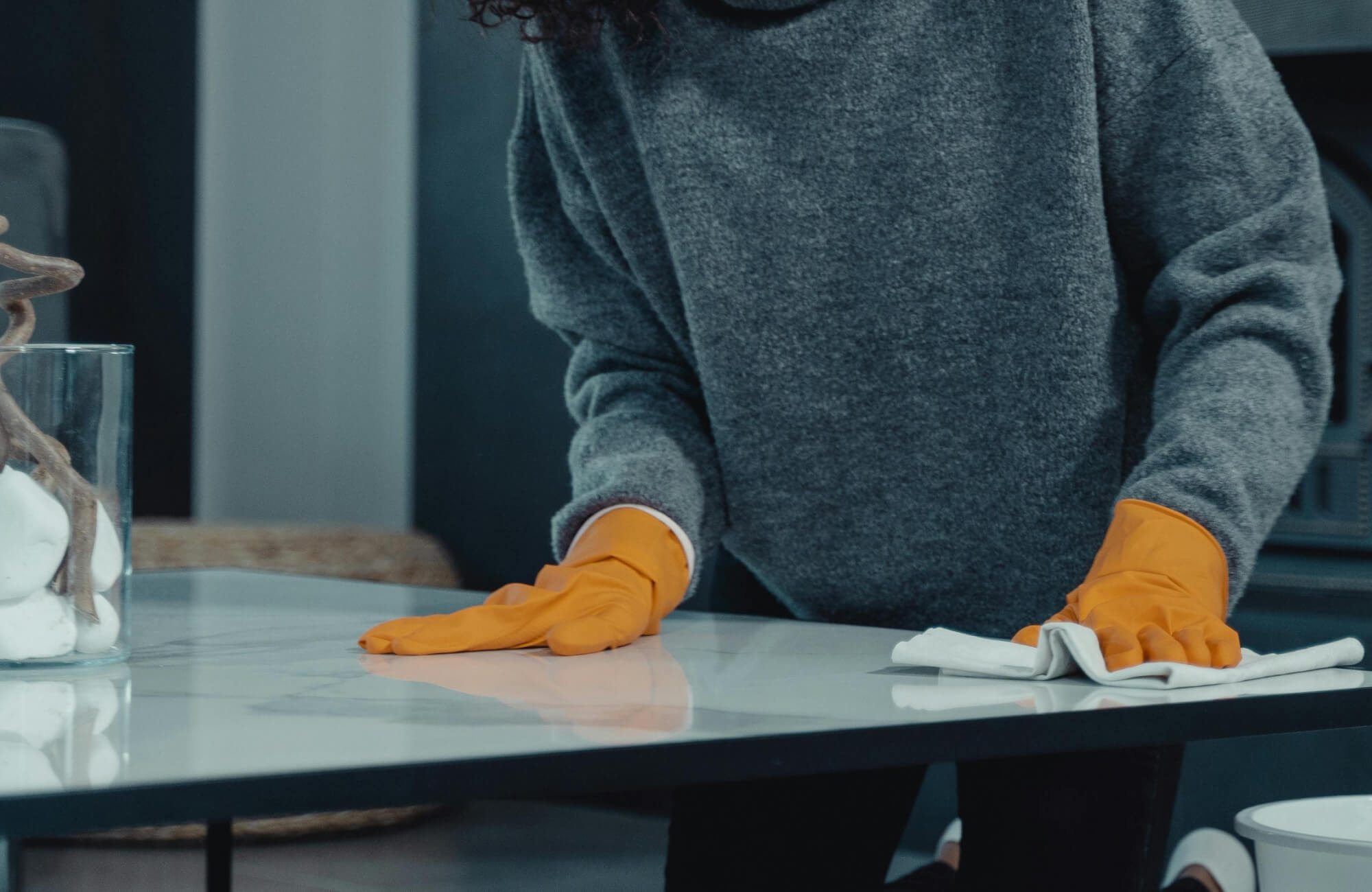 null Hands in protective gloves carefully wiping down a marble dining table, highlighting its smooth, polished surface and emphasizing cleanliness, durability, and everyday elegance.