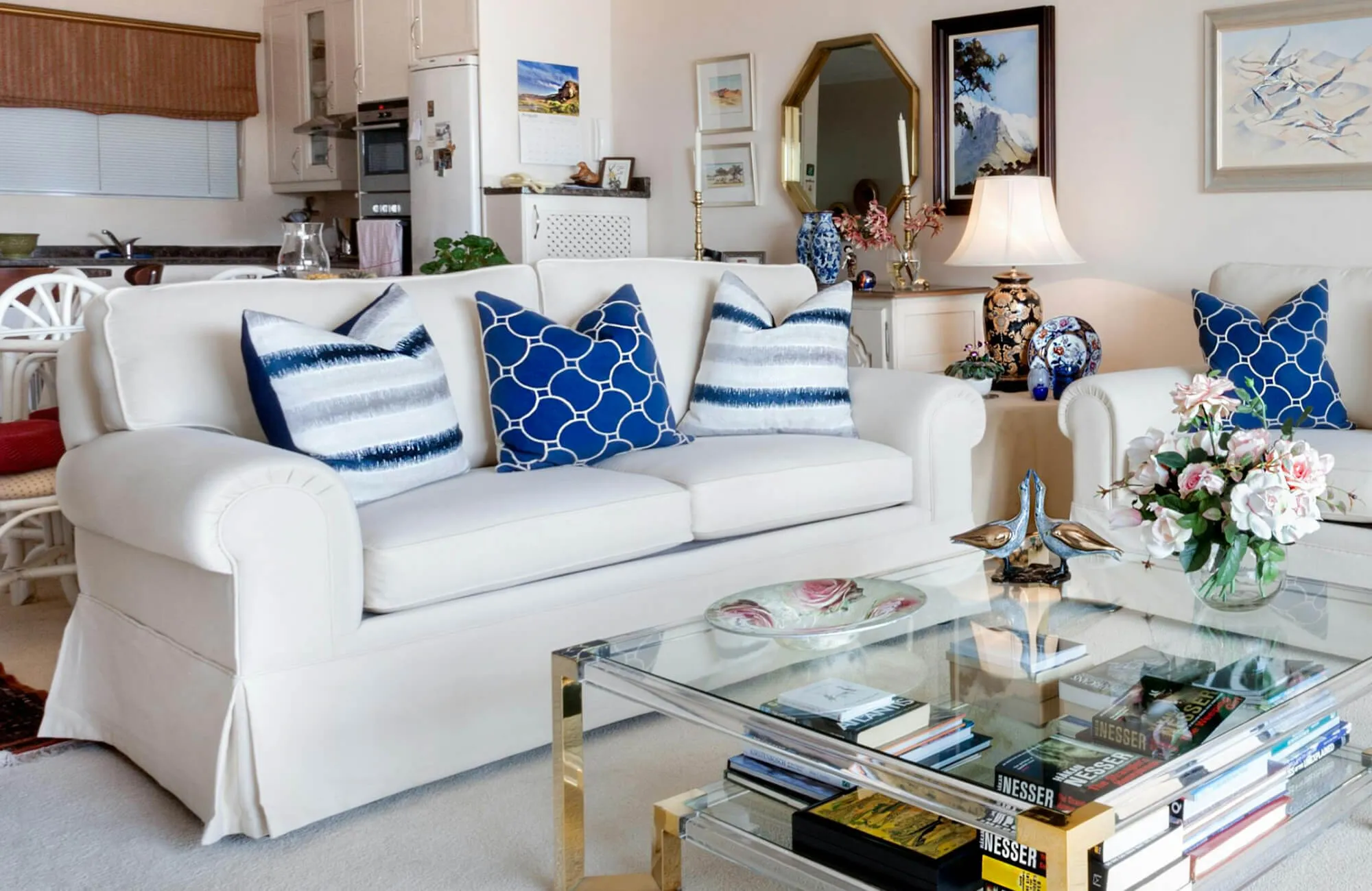 Blue and white decorative pillows with geometric and striped patterns arranged on a white living room sofa.