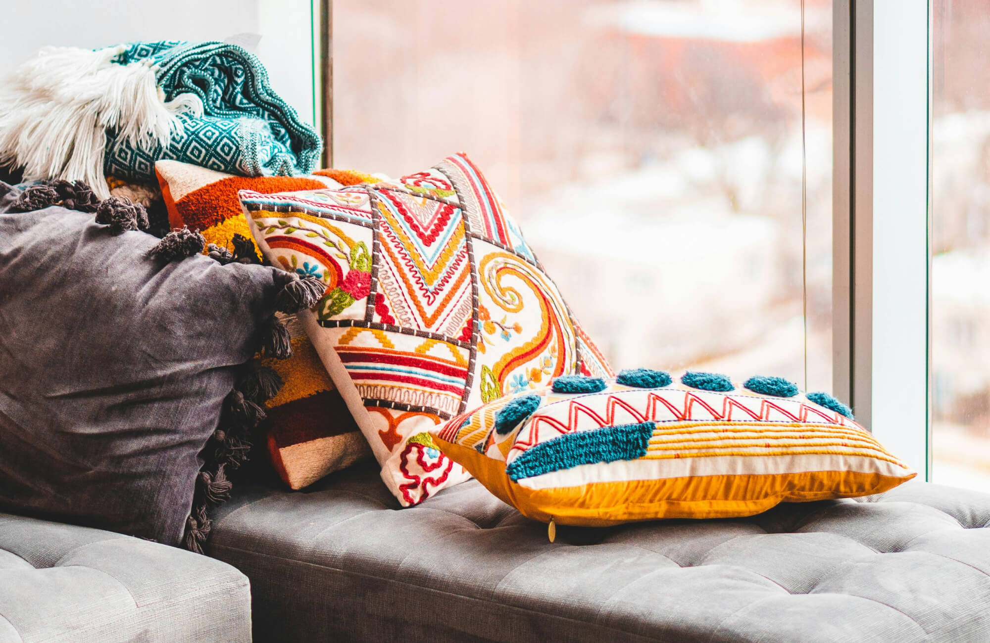 null Colorful embroidered decorative pillows with tassels and textured patterns arranged on a modern sofa.