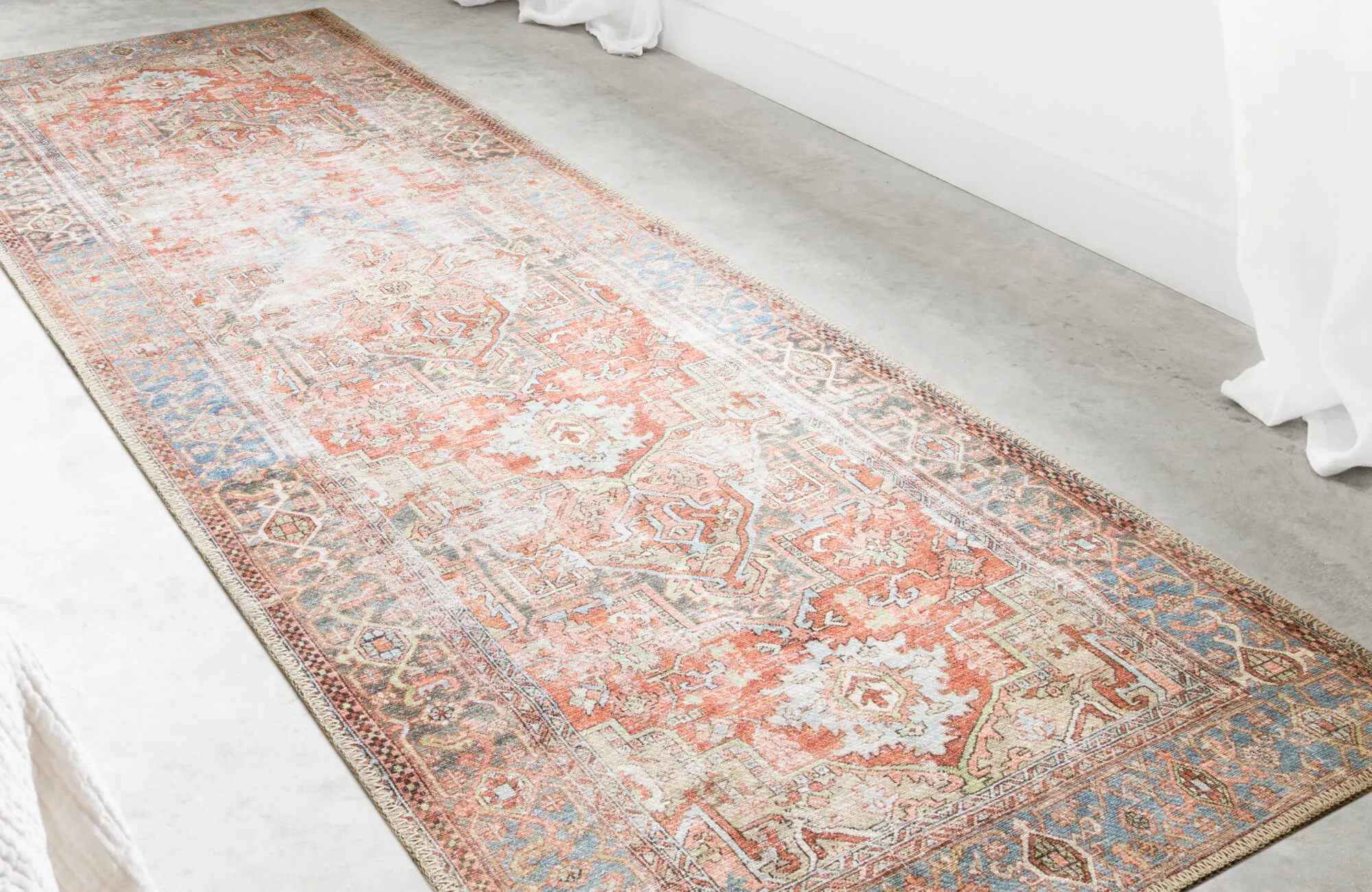Warm-toned vintage-style rug in coral, ivory, and blue hues adds instant coziness and charm to this bright minimalist room