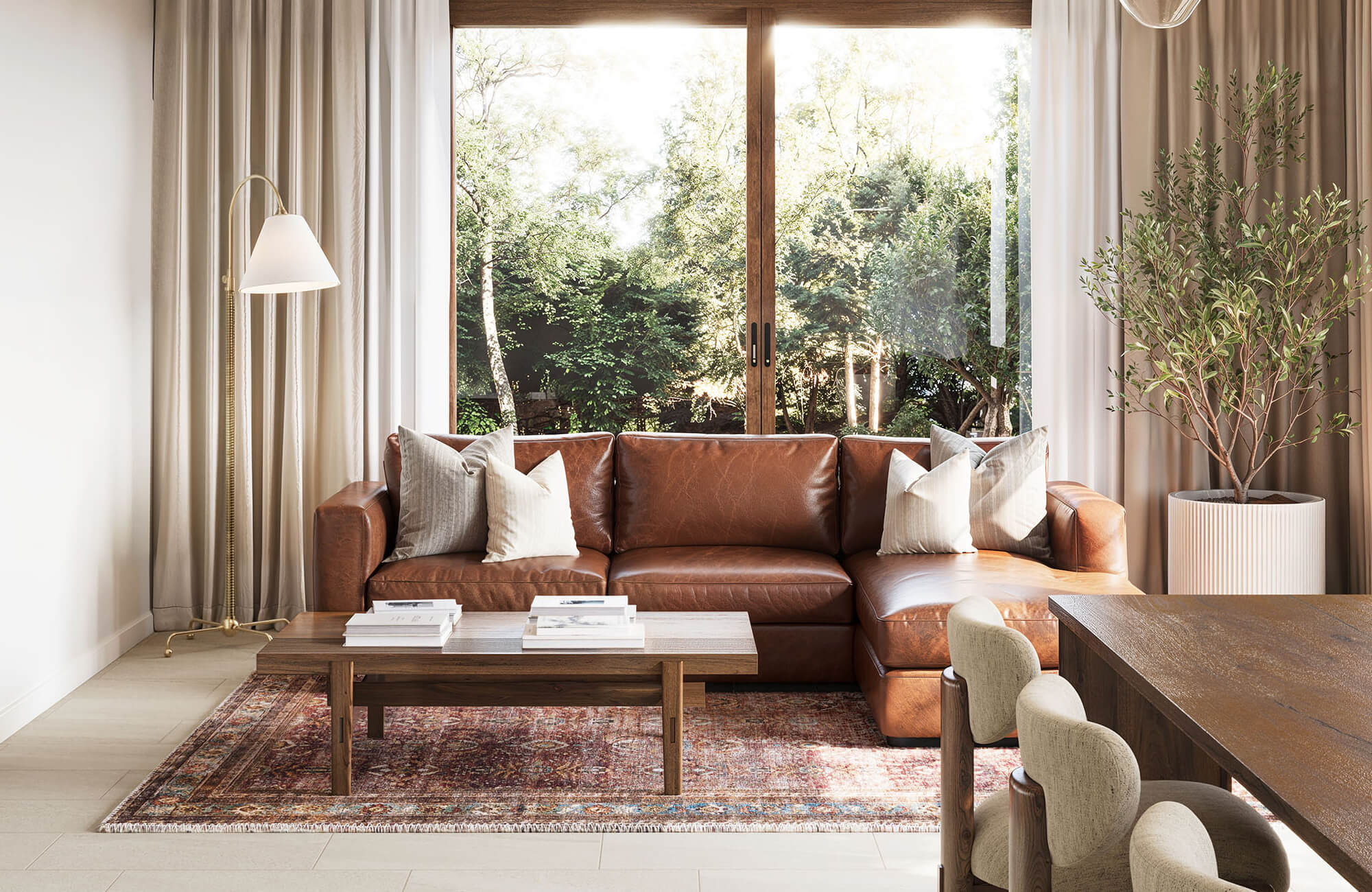Living room with tan floor tiles, brown leather sectional, vintage red area rug, wood coffee table, and floor-to-ceiling curtains