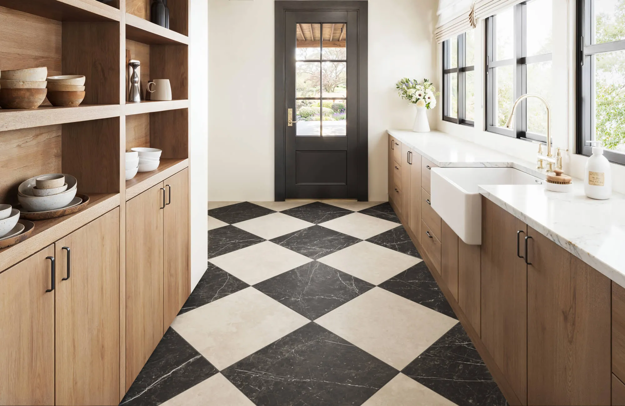 Bold black and white marble look checkered kitchen floor, warm wood cabinetry, and elegant brass fixtures.